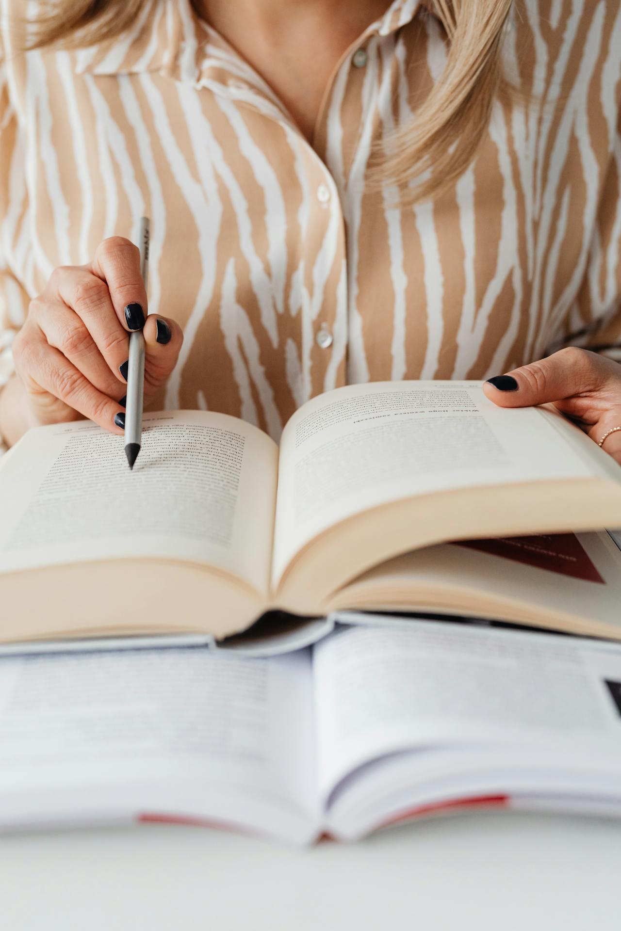 mulher a apontar com caneta para um livro