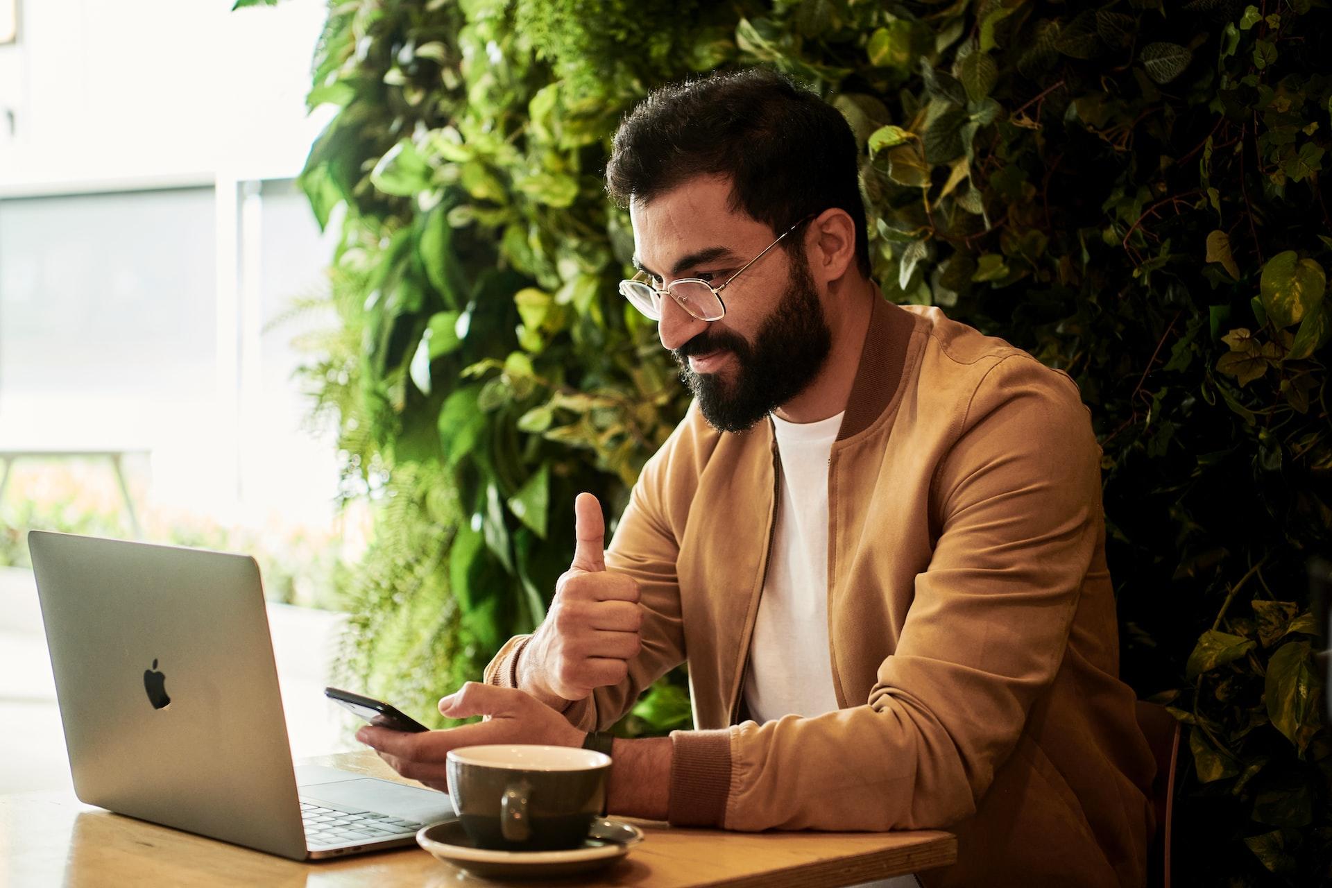 Rapaz a olhar para o computador e com chávena de café