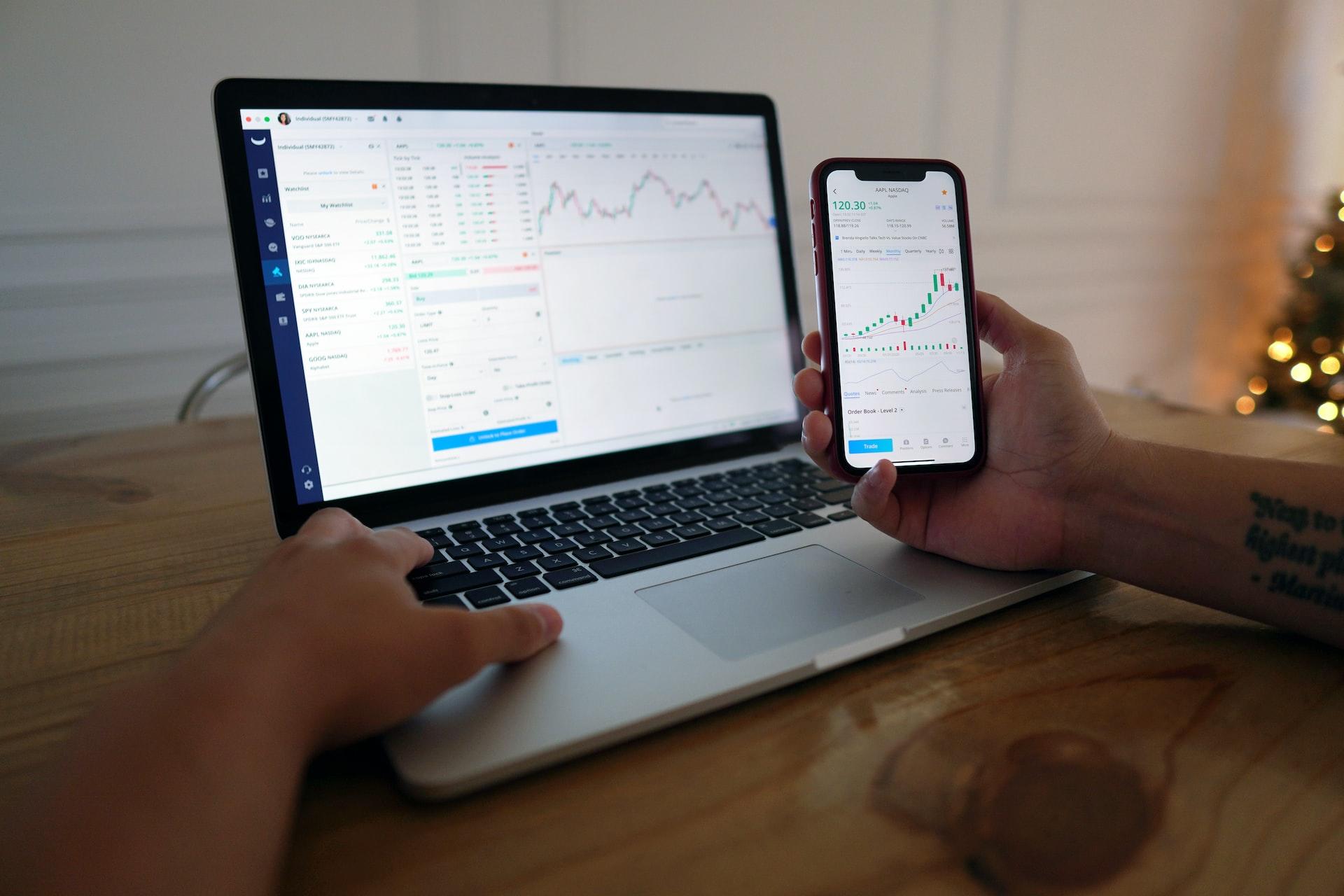 Mão com telemóvel e computador