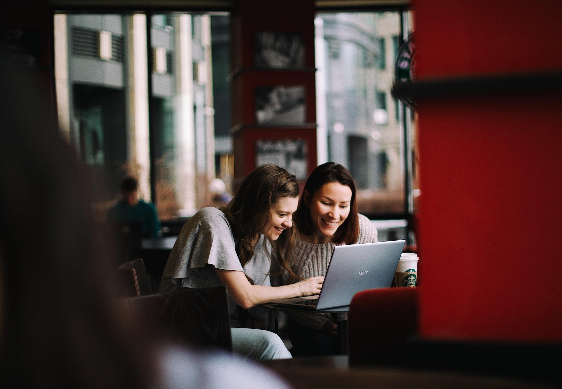Duas mulheres a sorrir e a olhar para um computador