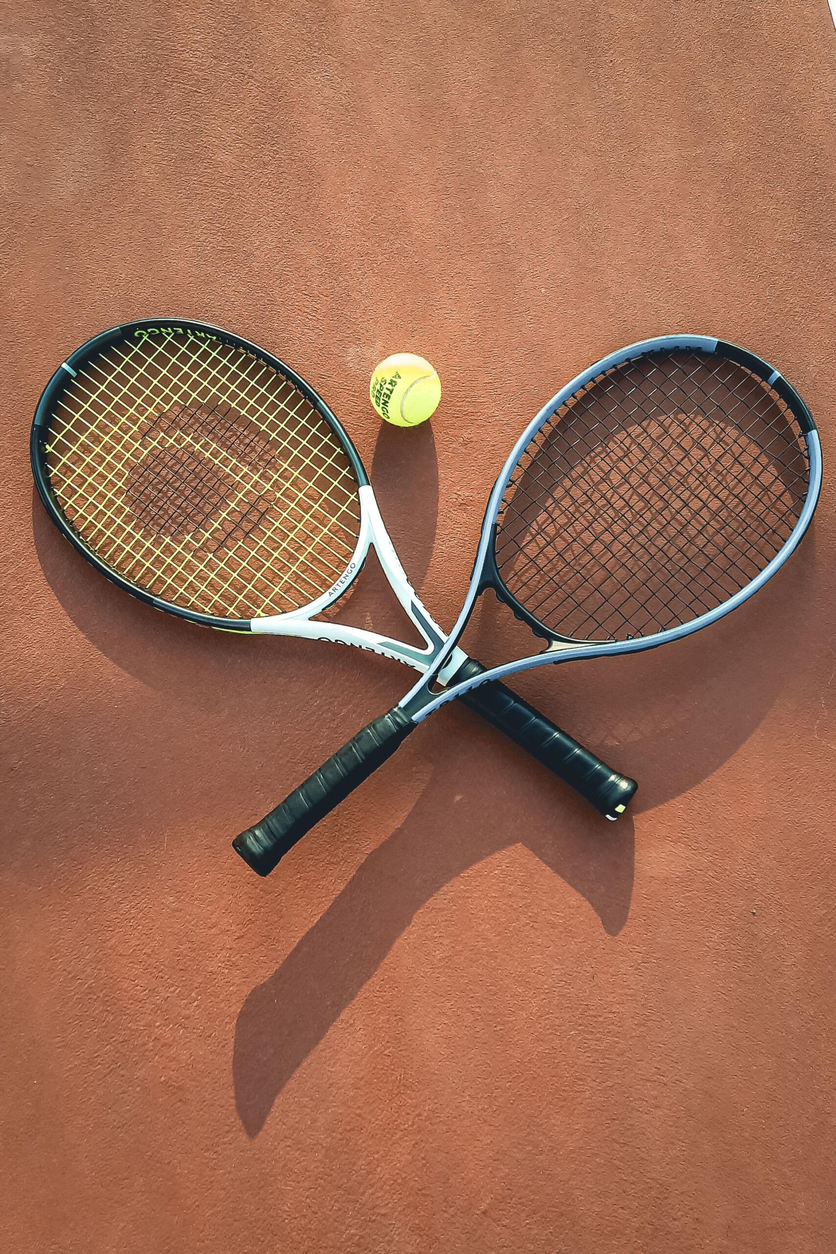 duas raquetes pousadas no chão, com uma bola