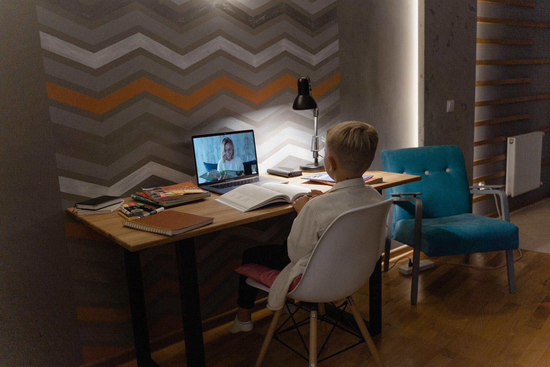jovem sentado em frente ao computador com livro aberto