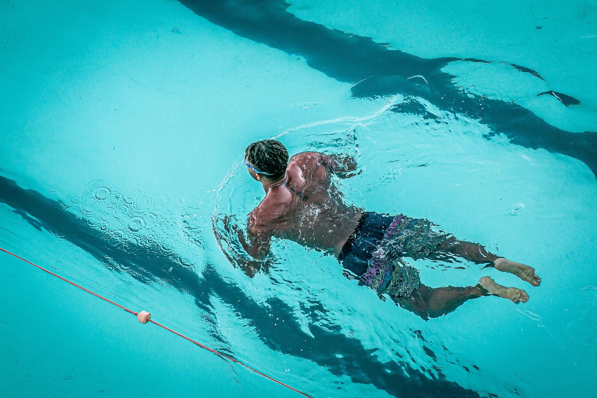 homem dentro de piscina com touca