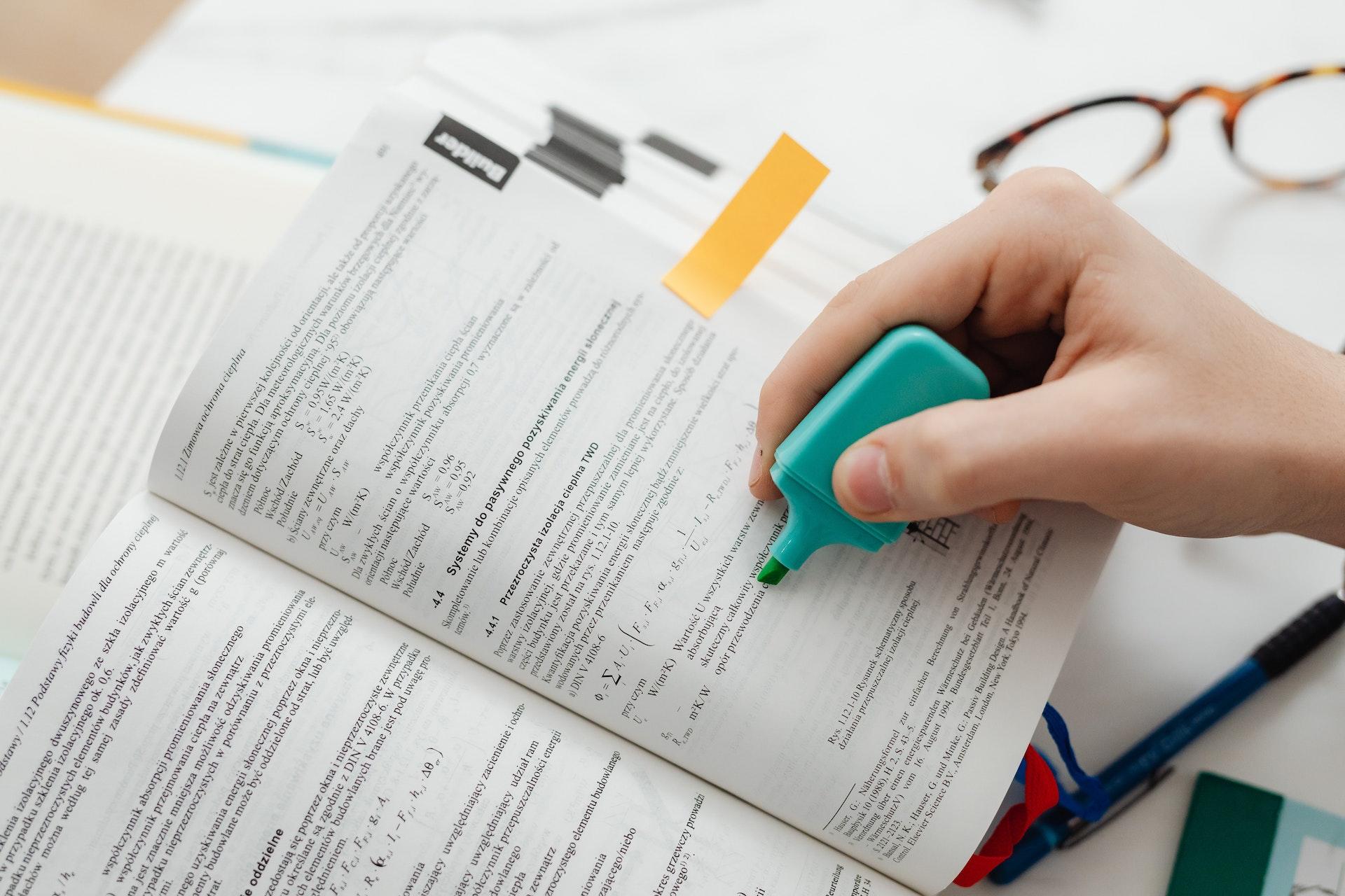 pessoa a assinalar livro com marcador