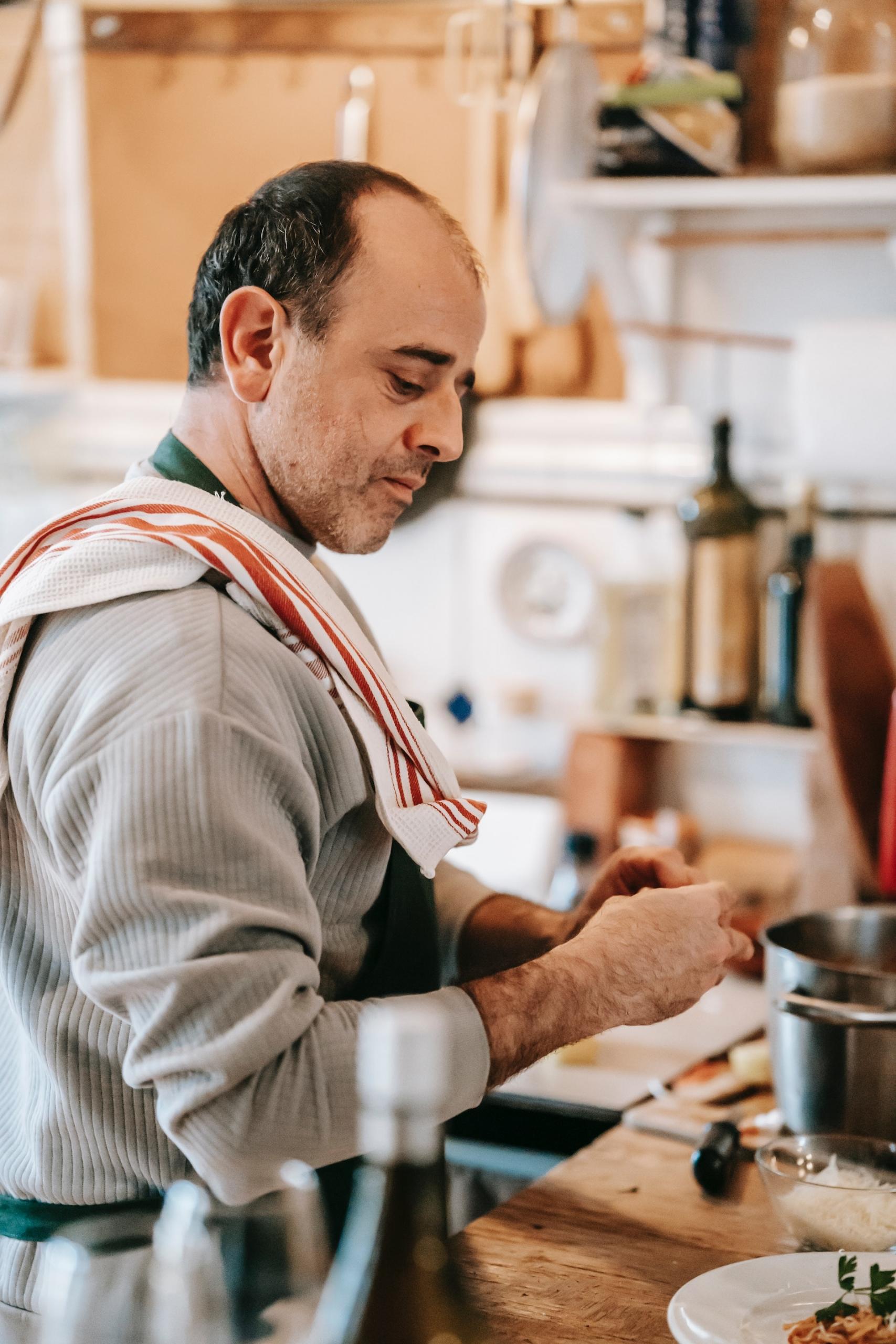 homem de avental na cozinha junto a um tacho