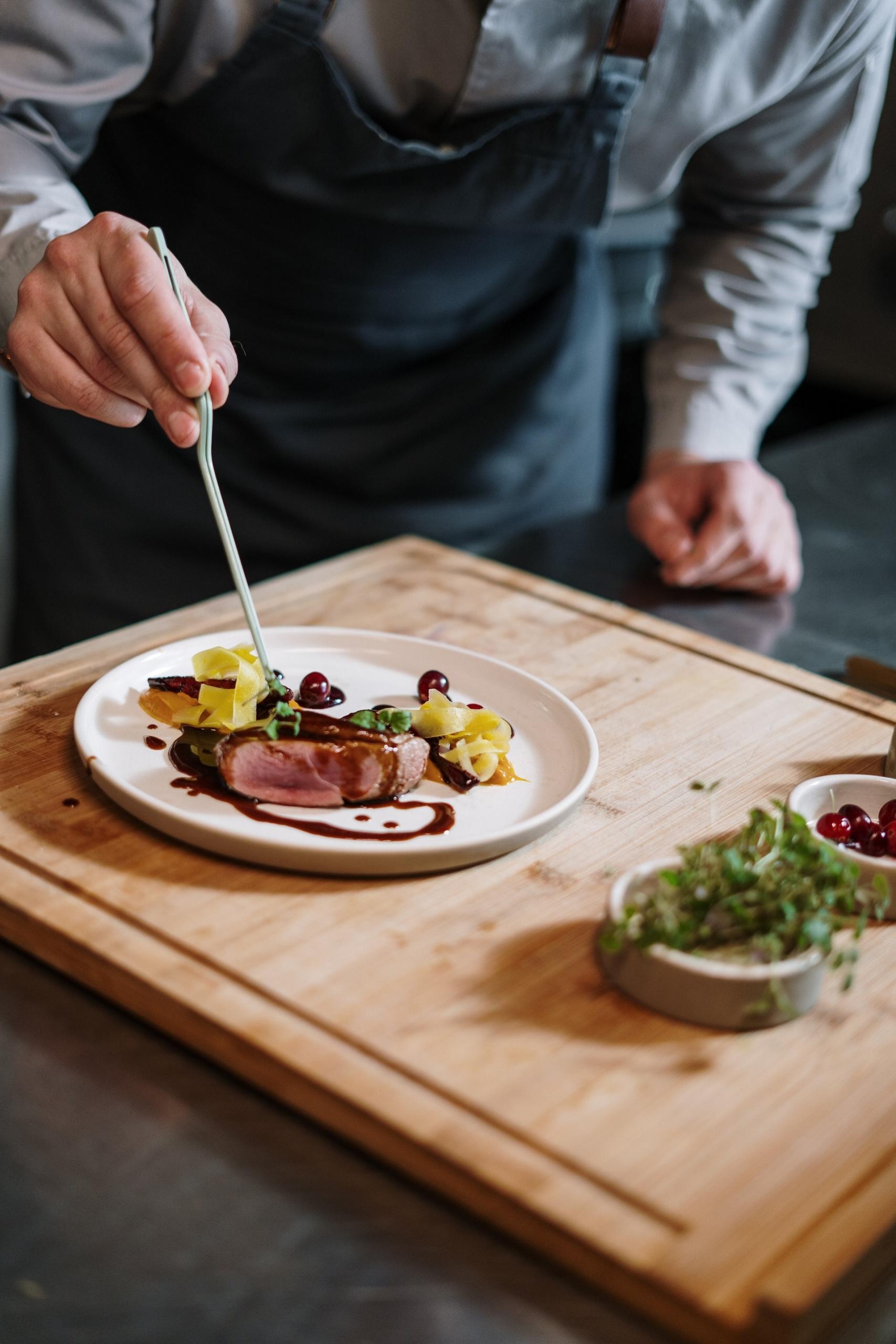 pessoa a colocar molho num prato com carne