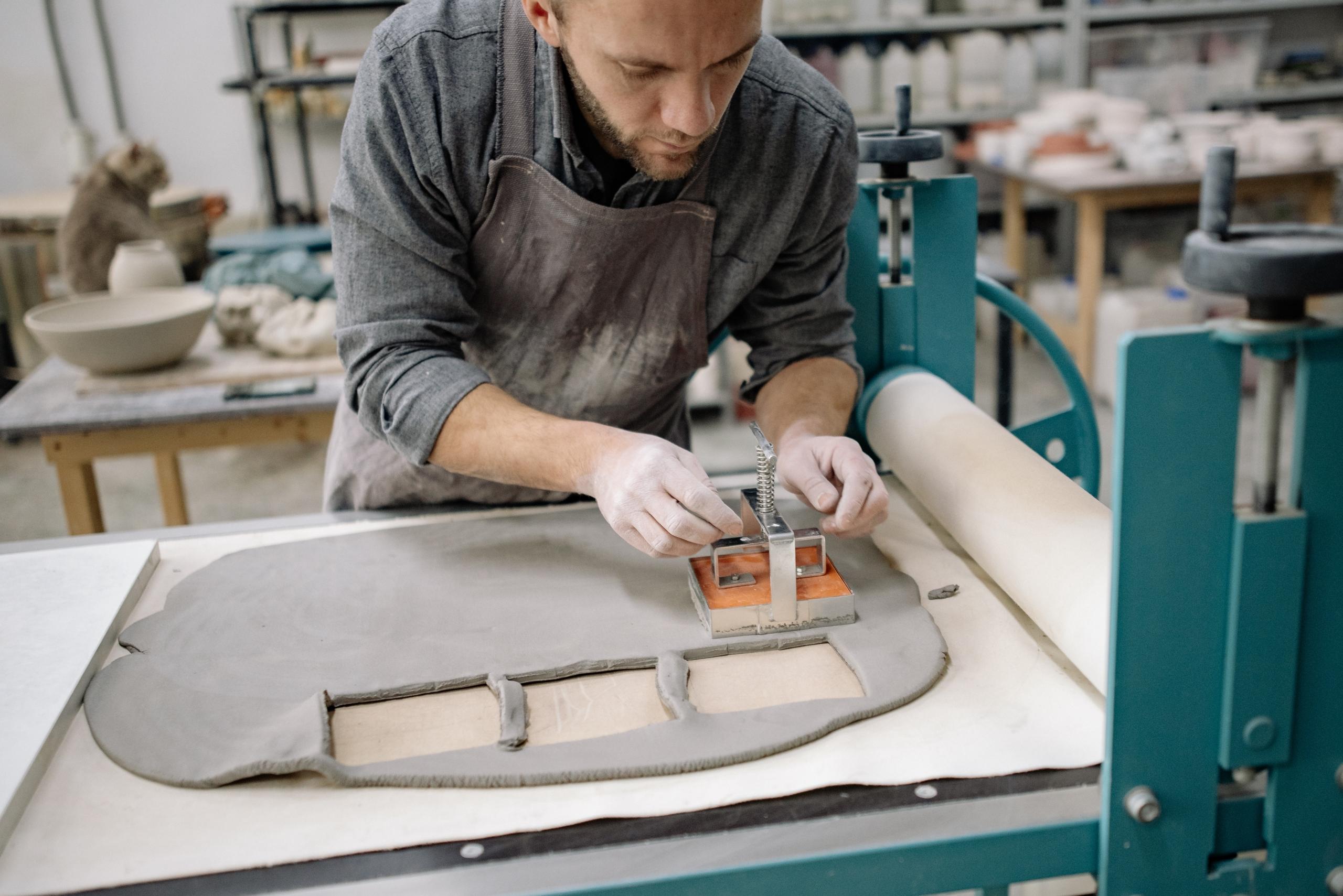 pessoa a cortar barro com um molde