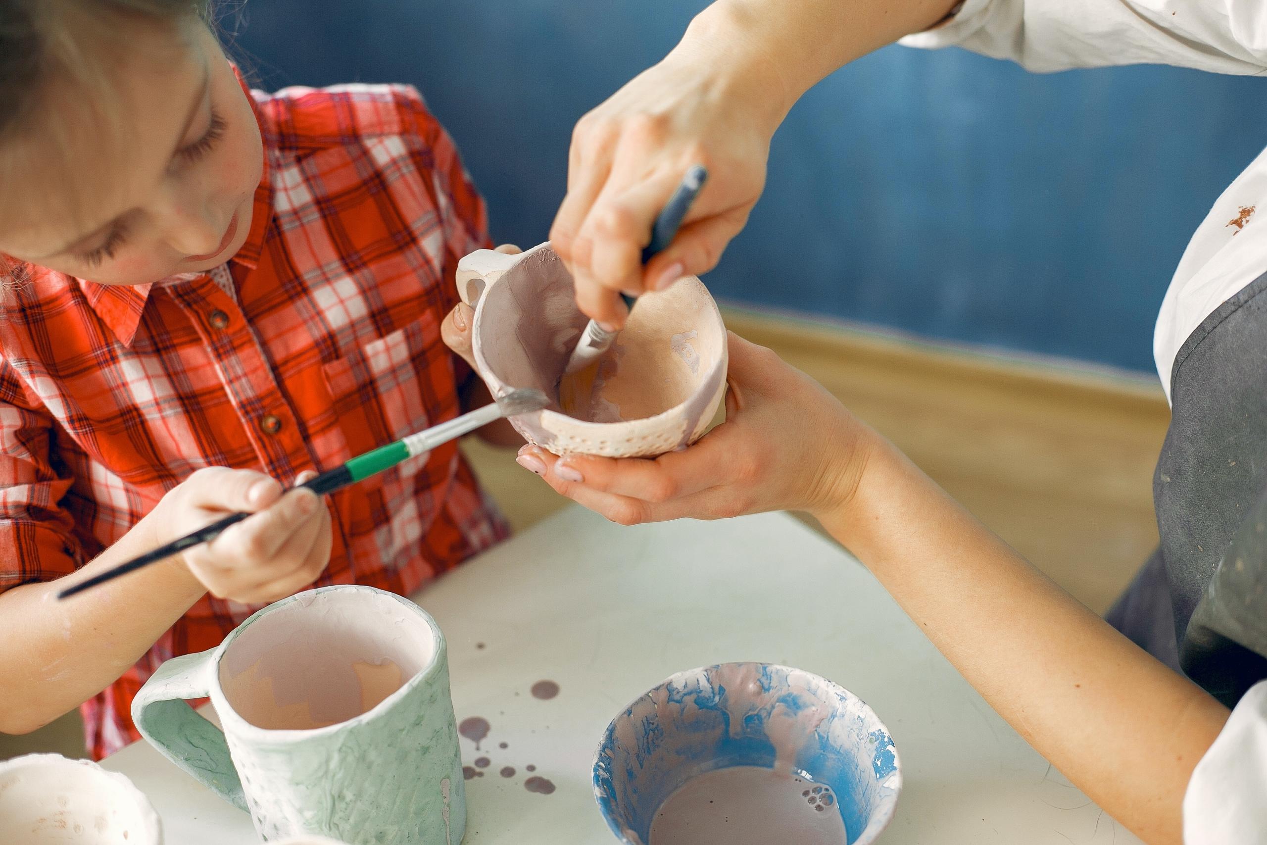 crianca e adulto a pintar uma caneca