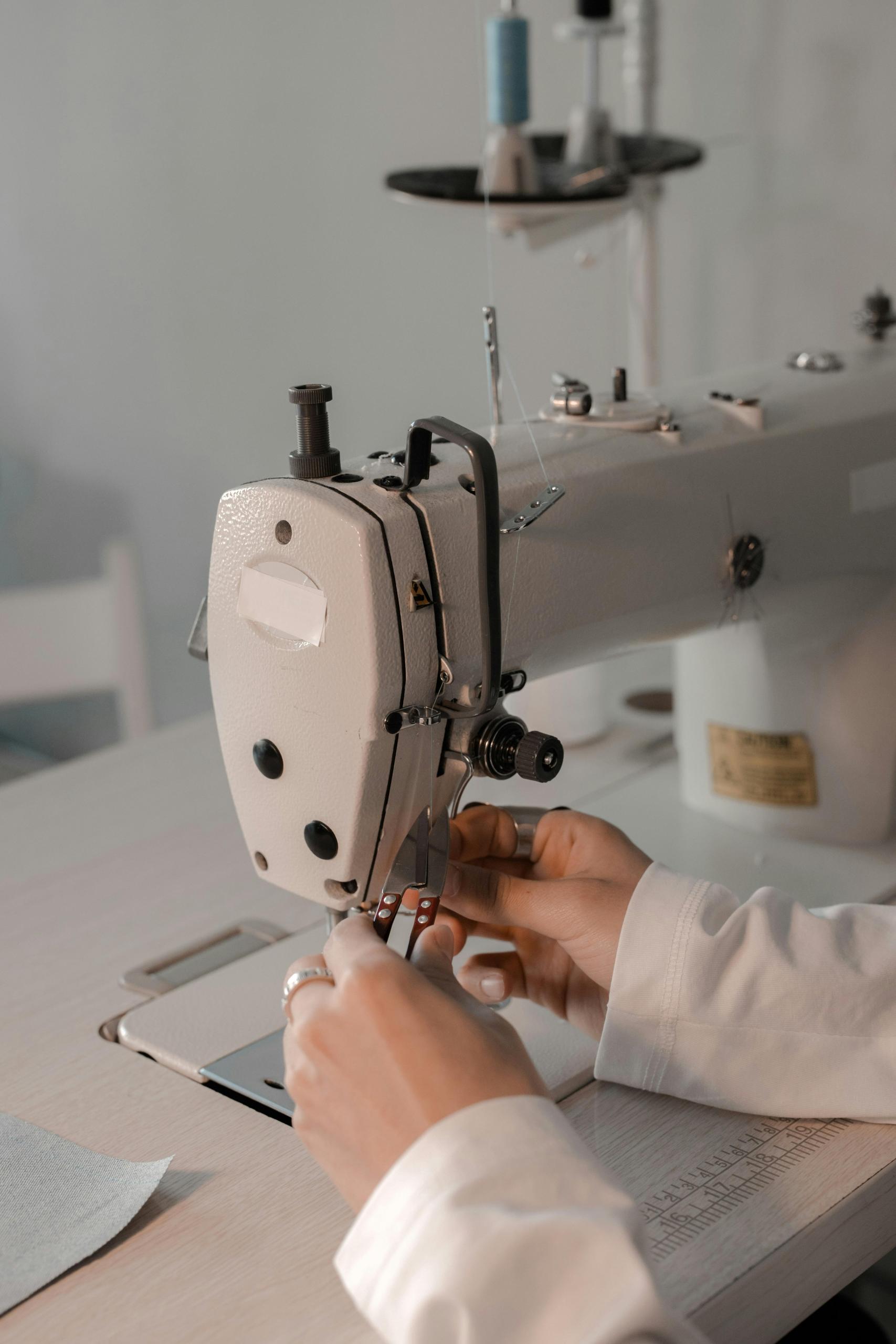 pessoa a enfiar linha na agulha da máquina