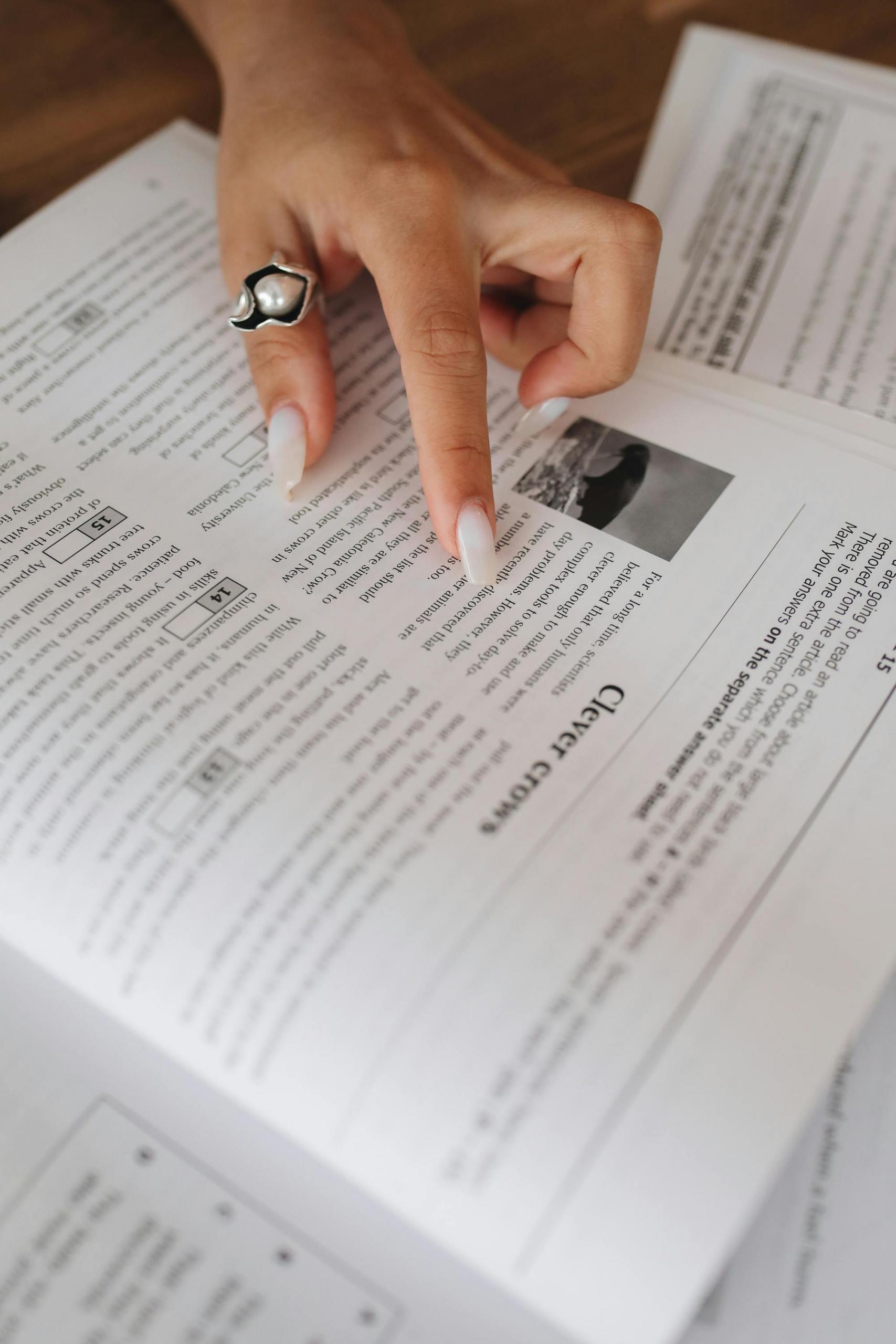 mulher com unhas brancas a apontar para folha de livro