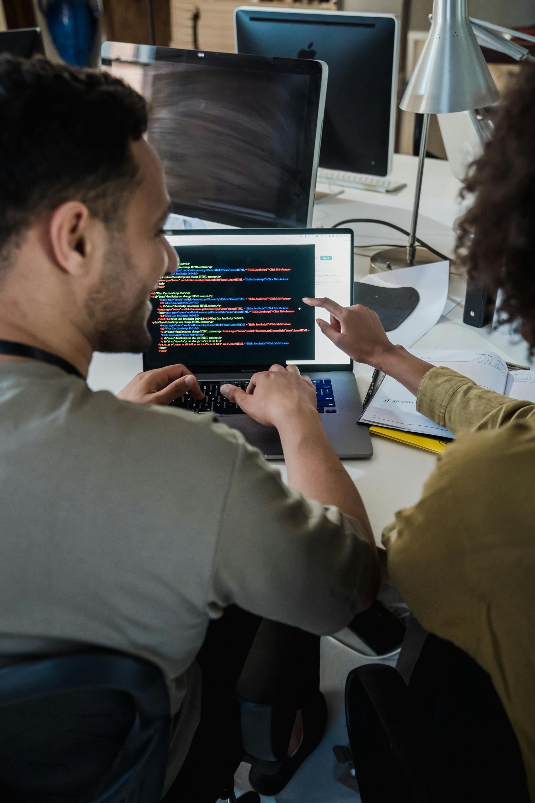 duas pessoas a apontar para computador com código