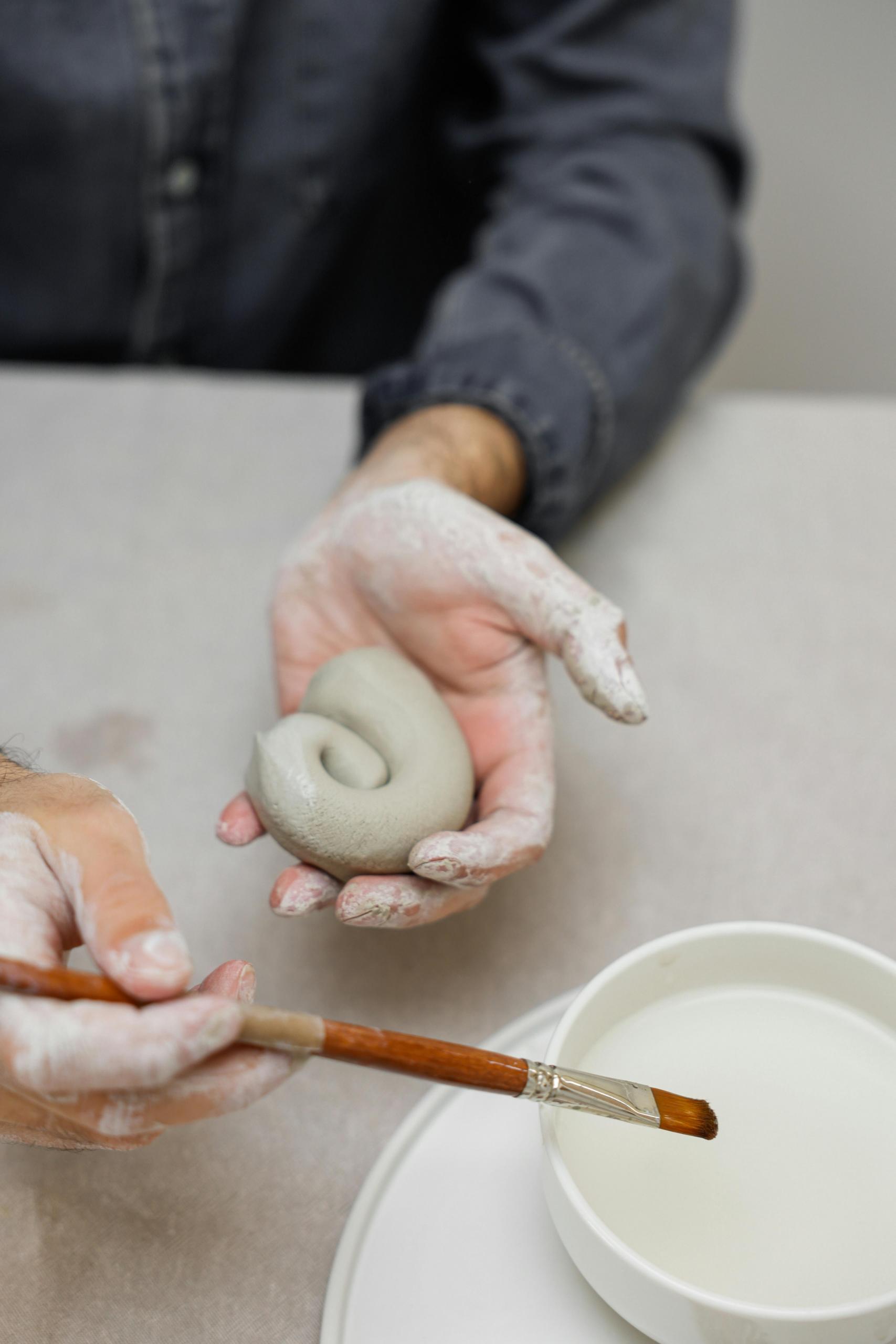 pessoa com rolo de argila e um pincel
