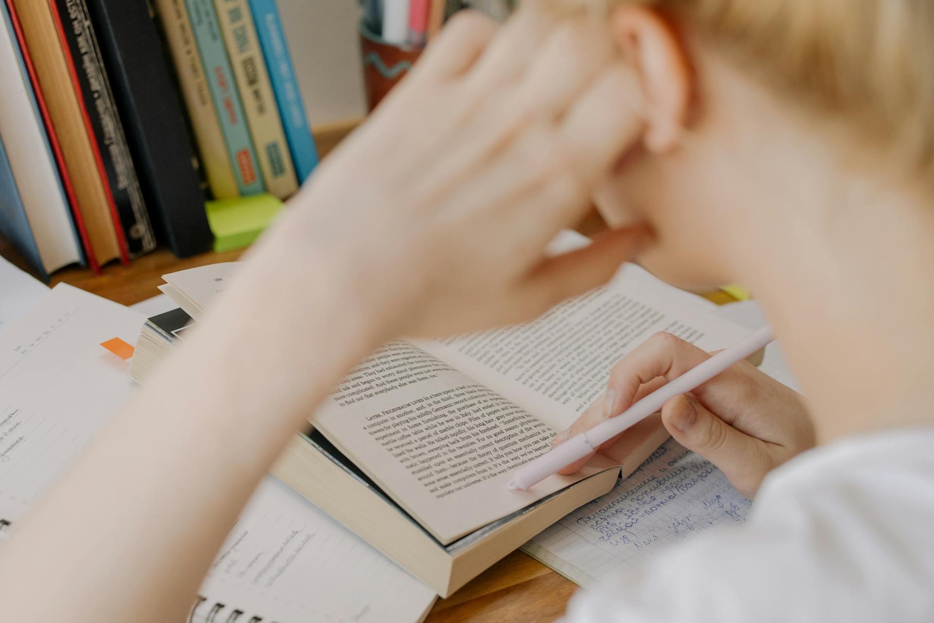 rapariga a ler um livro aberto com caneta a segurar a página