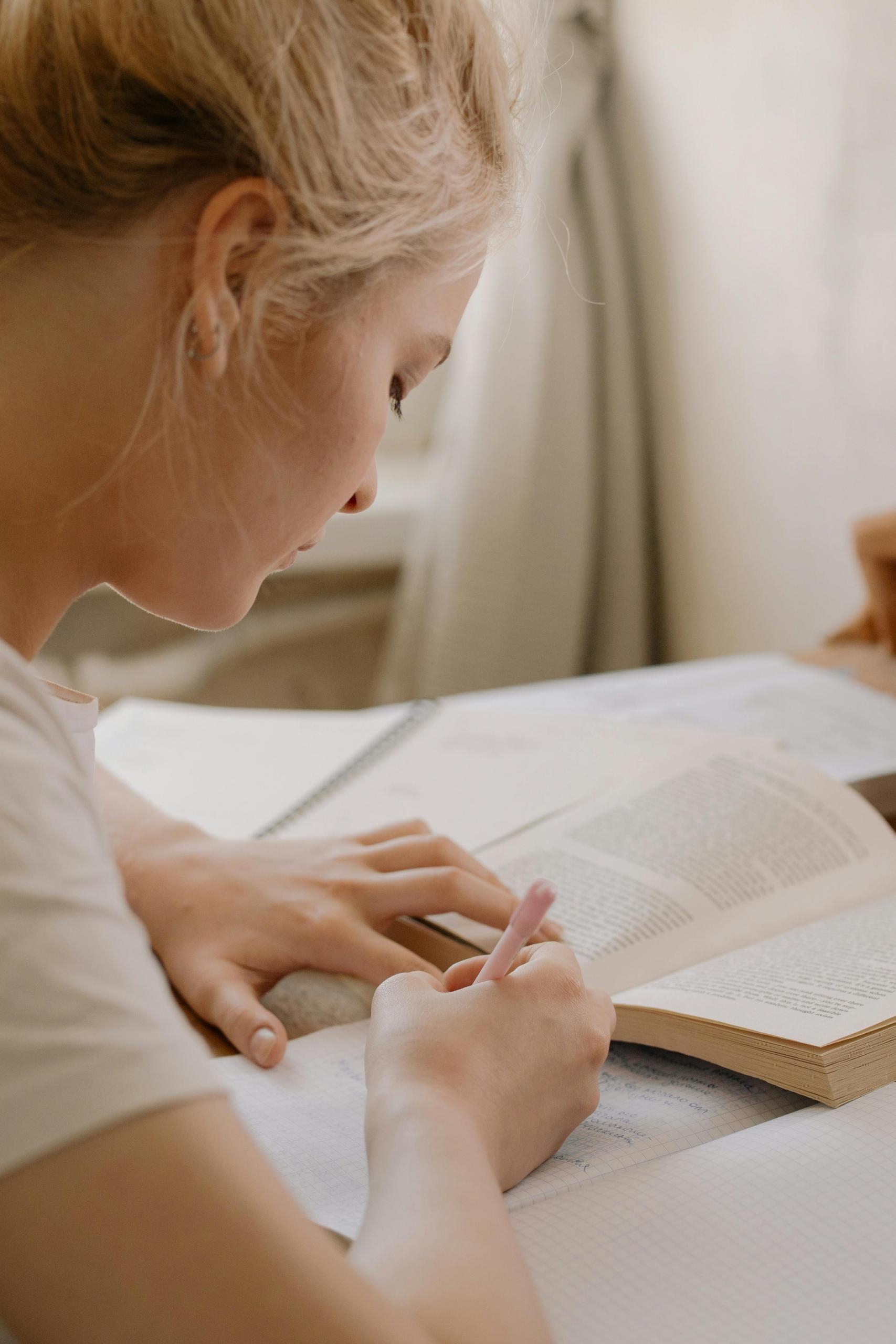 mulher a escrever em caderno com livro aberto