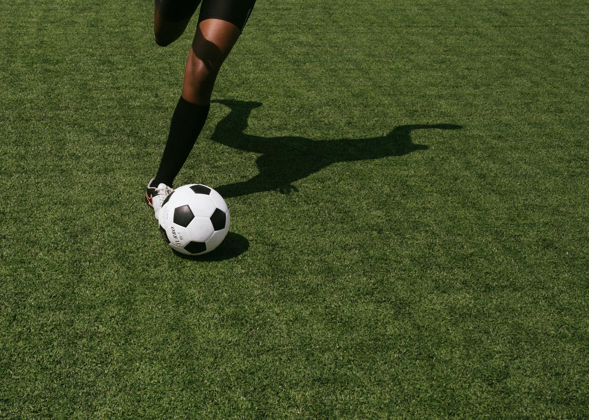 pés de jogador a chutar uma bola no campo