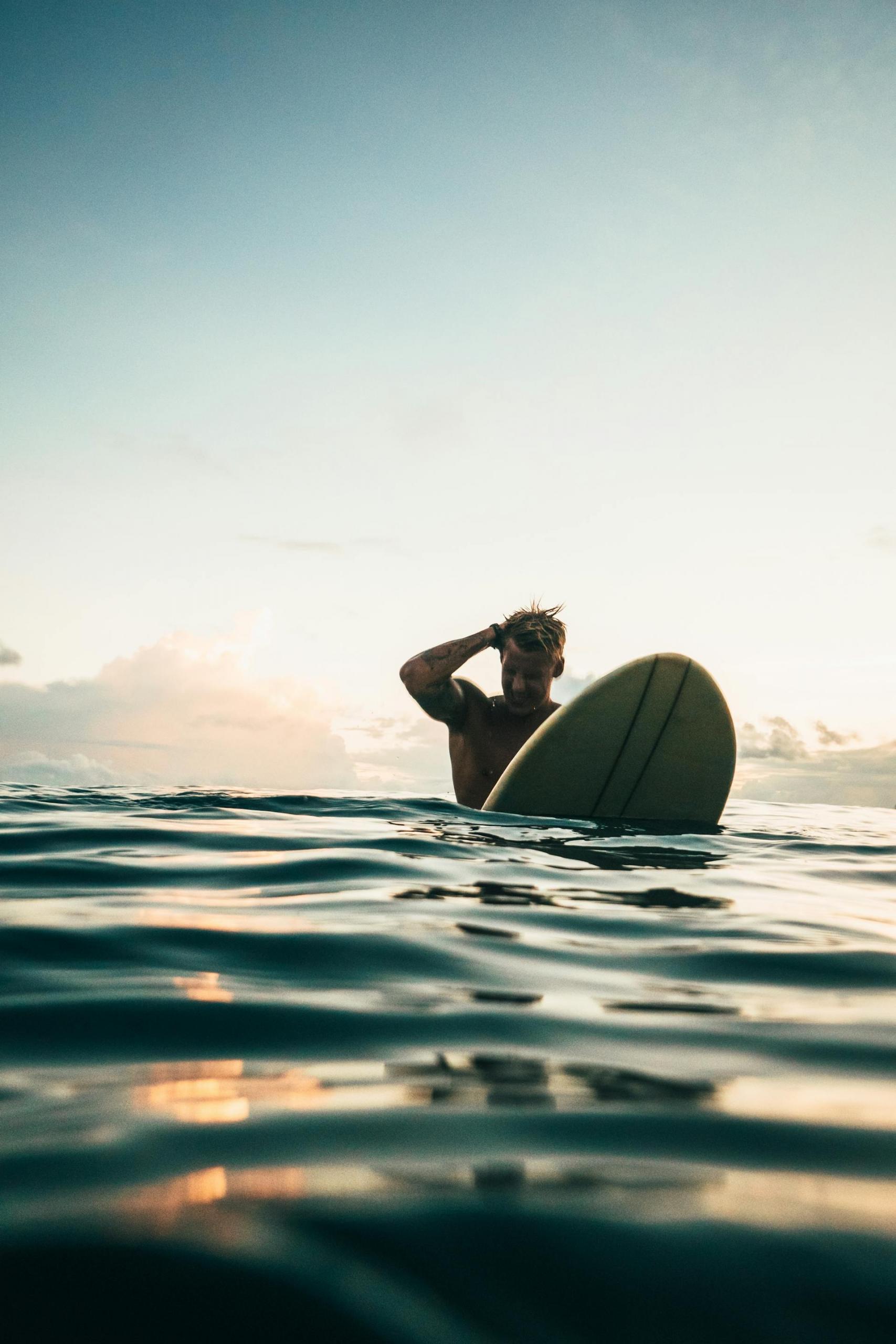 surfista dentro de água ao por do sol