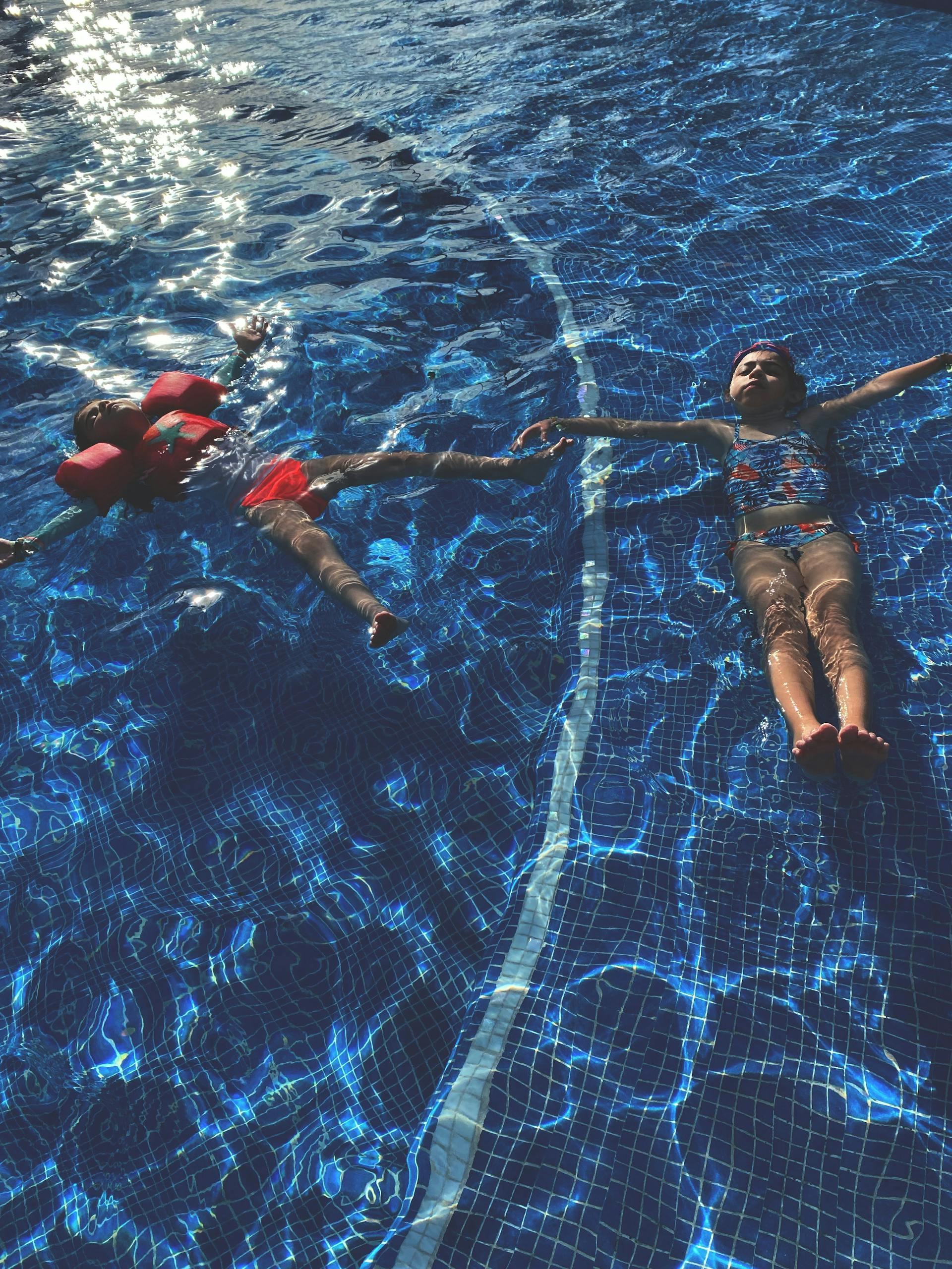duas crianças a flutuar na piscina