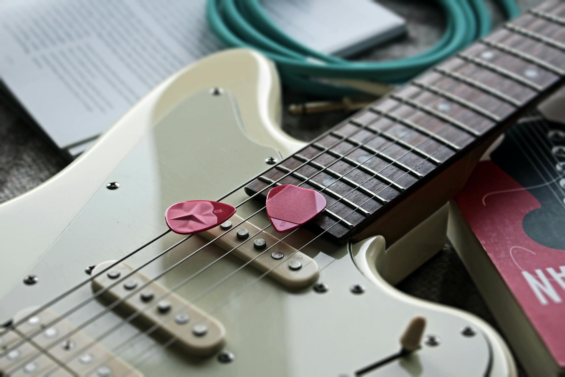 guitarra branca com duas palhetas cor de rosa