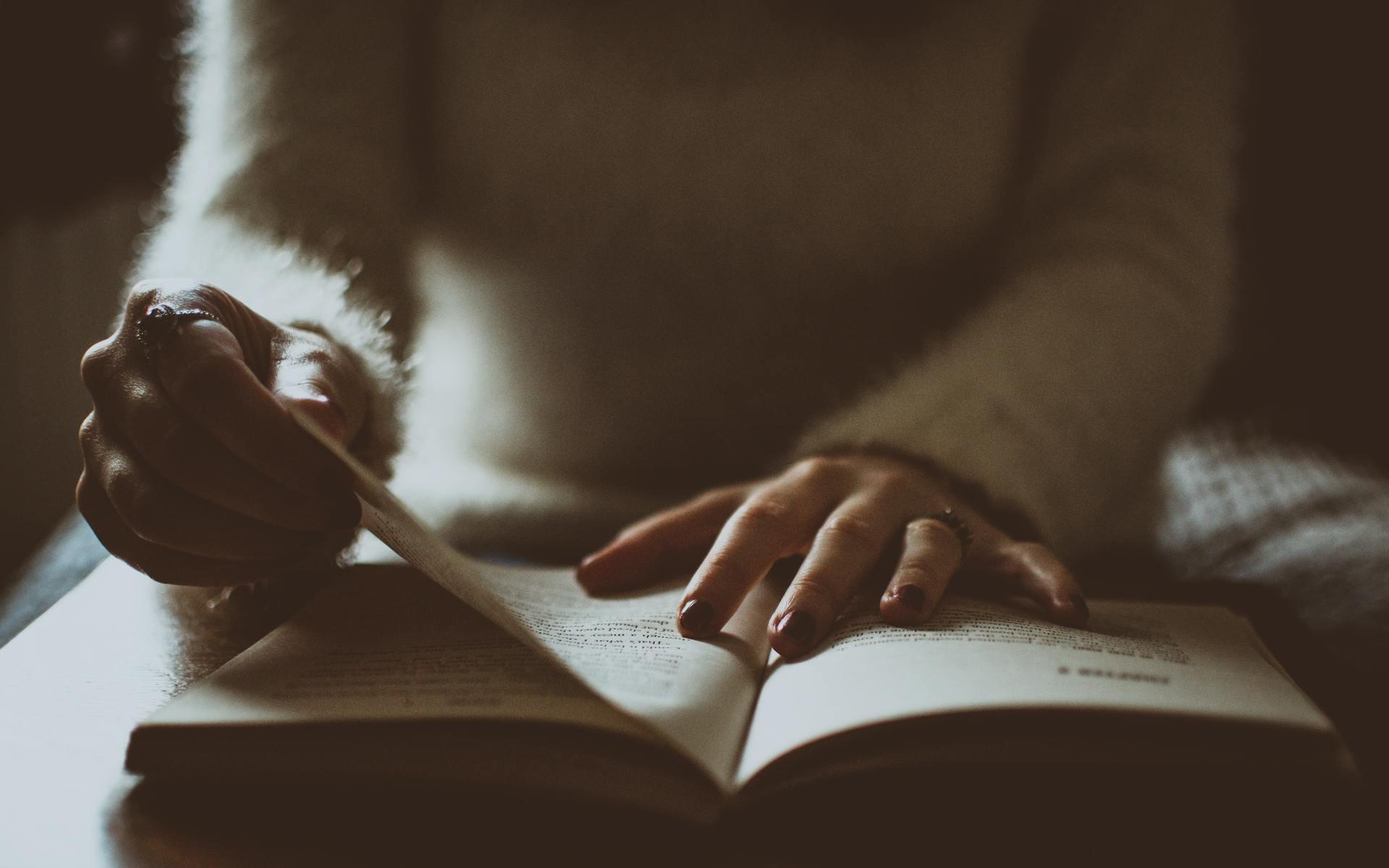 mulher com unhas pintadas a mexer em livro