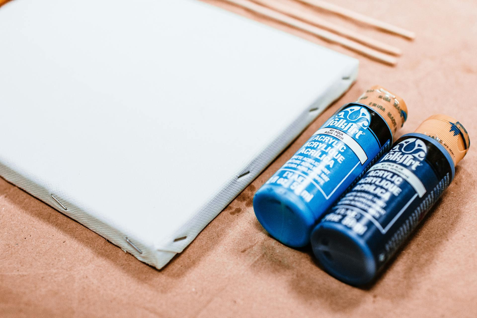 tela branca e dois frascos de tinta