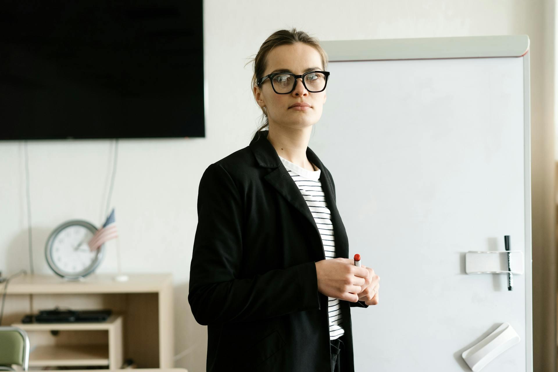 mulher de blazer preto em frente a quadro branco