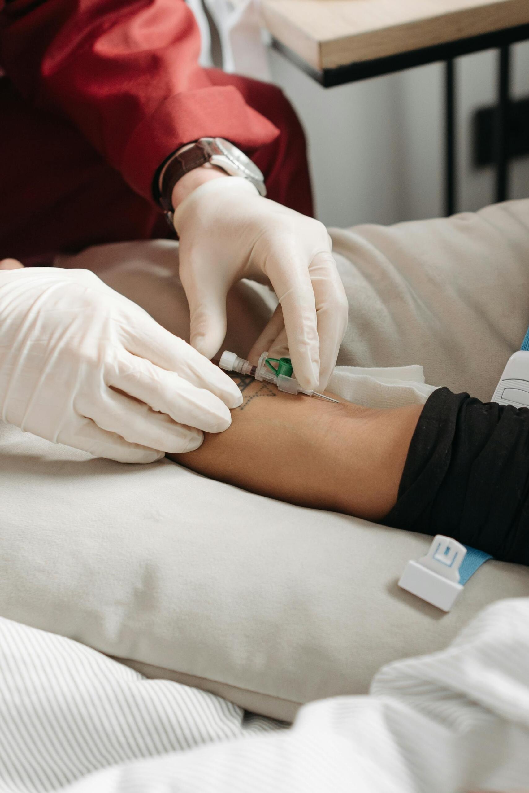 mãos com luvas a inserir seringa num braço