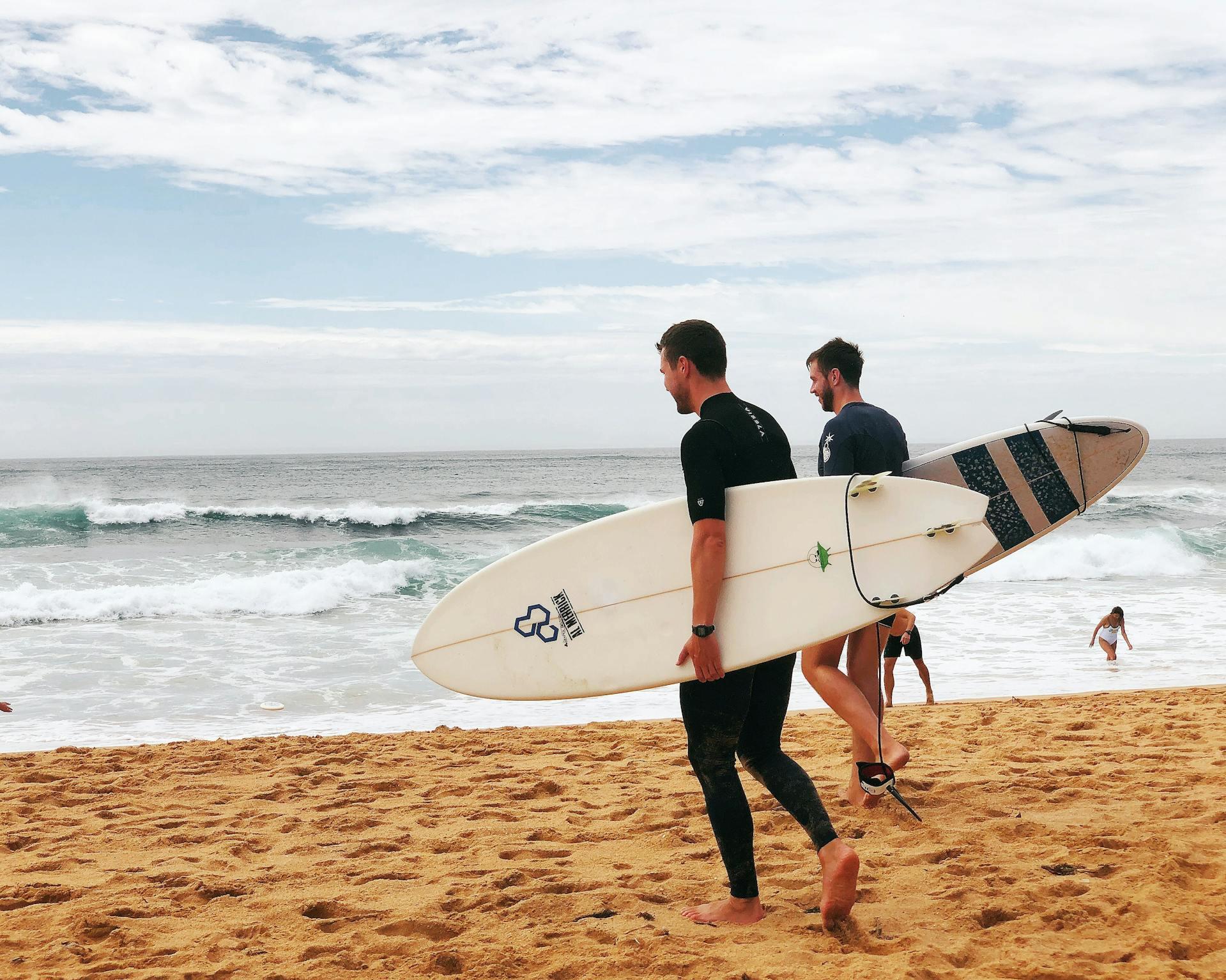 dois surfistas com prancha na praia