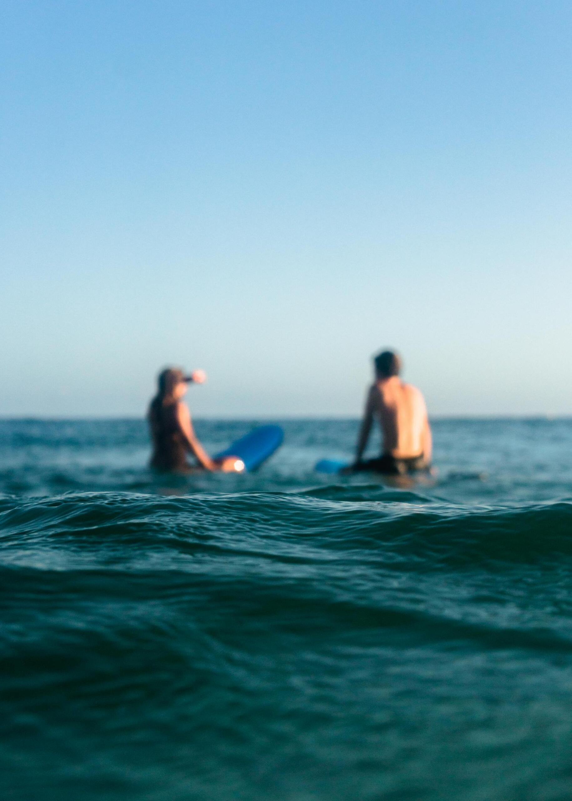 duas pessoas em cima da prancha no mar