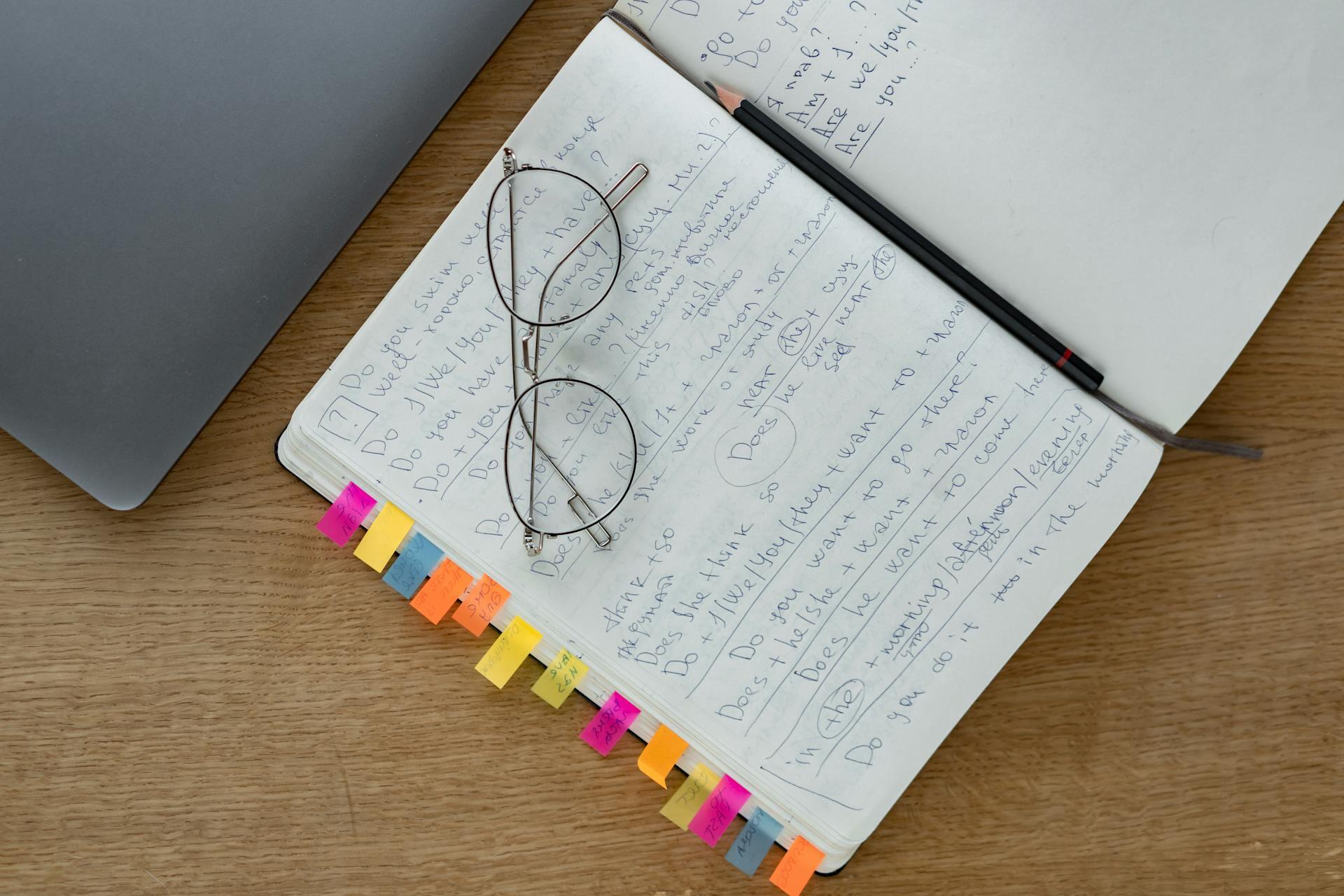 caderno com apontamentos e óculos de leitura