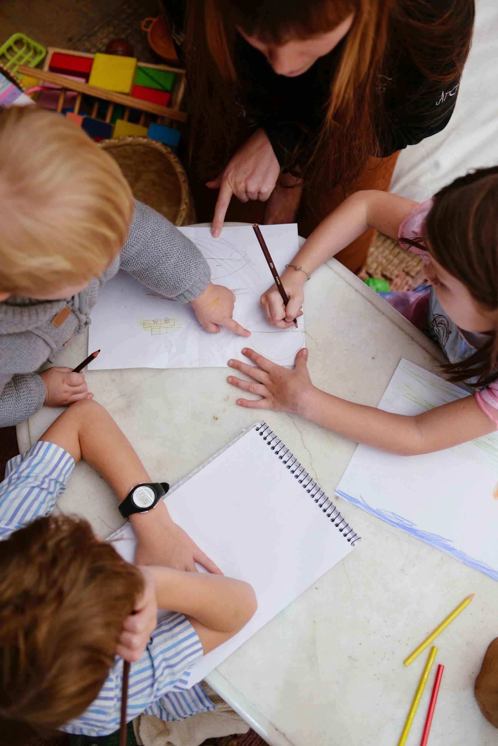 várias crianças com cadernos e lápis numa mesa