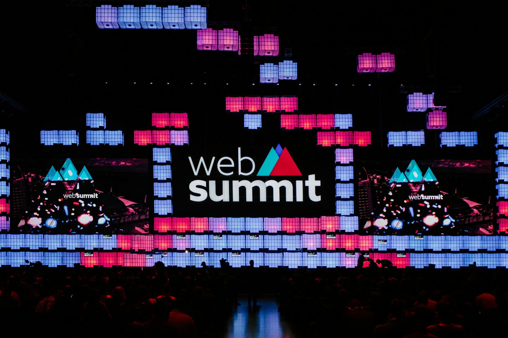 painel com web summit escrito e várias luzes