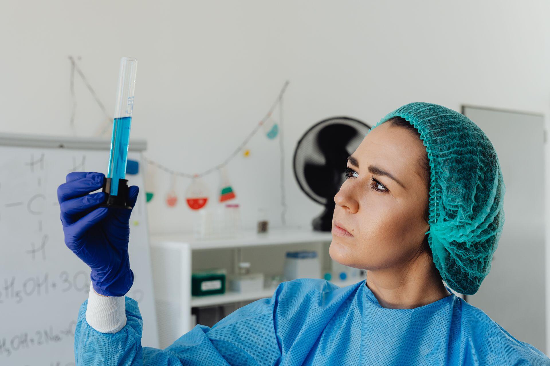 mulher em laboratório de touca a segurar em tubo com líquido
