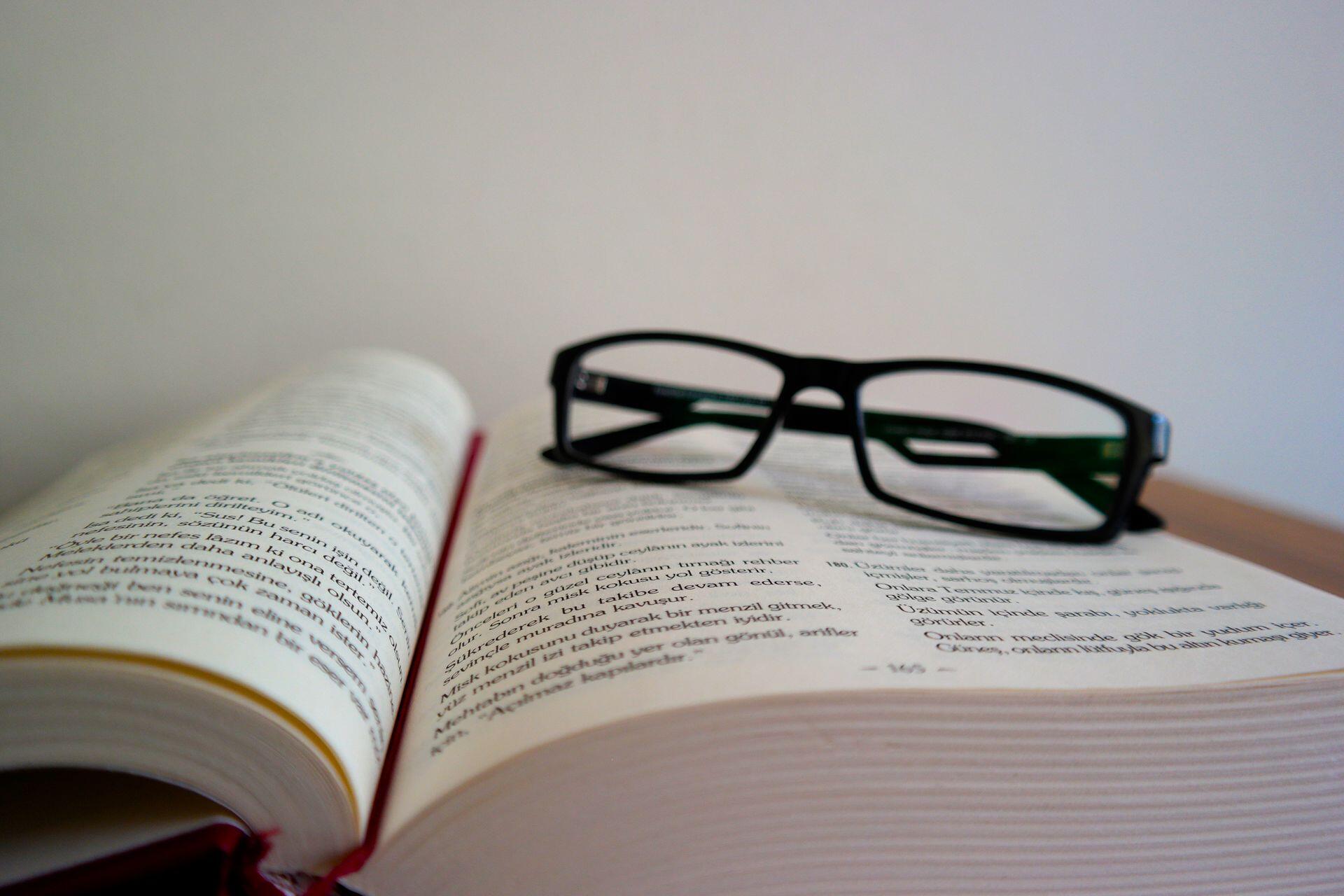 óculos pretos com livros abertos