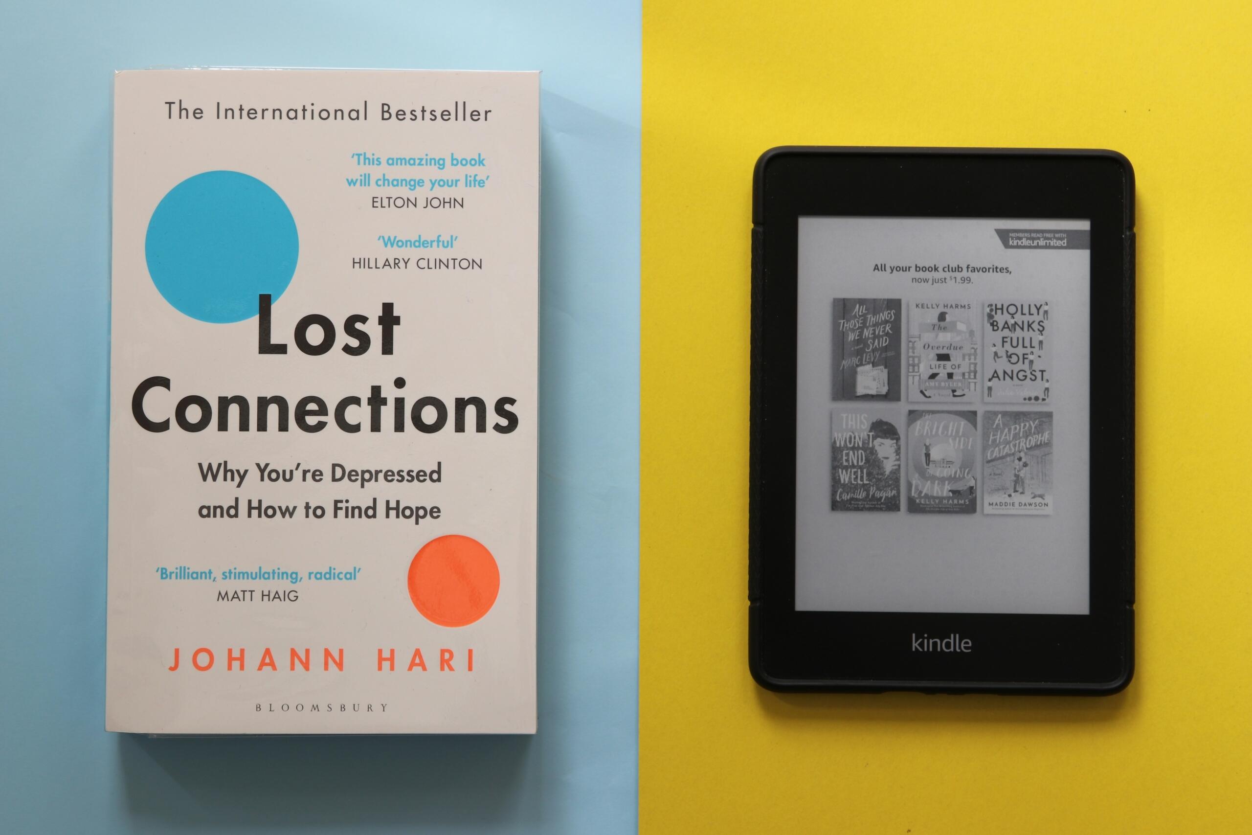 كتاب ورقي بعنوان  بجانب جهاز "Kindle" للقراءة الإلكترونية وخلفهما خلفية منقسمة باللونين الأزرق والأصفر.