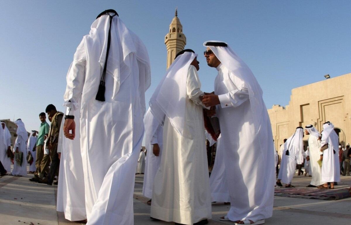 رجال قطريون يتبادلون التهاني والتحية صباح عيد الأضحى، مرتدين الثوب والغترة التقليدية وسط أجواء احتفالية دافئة.