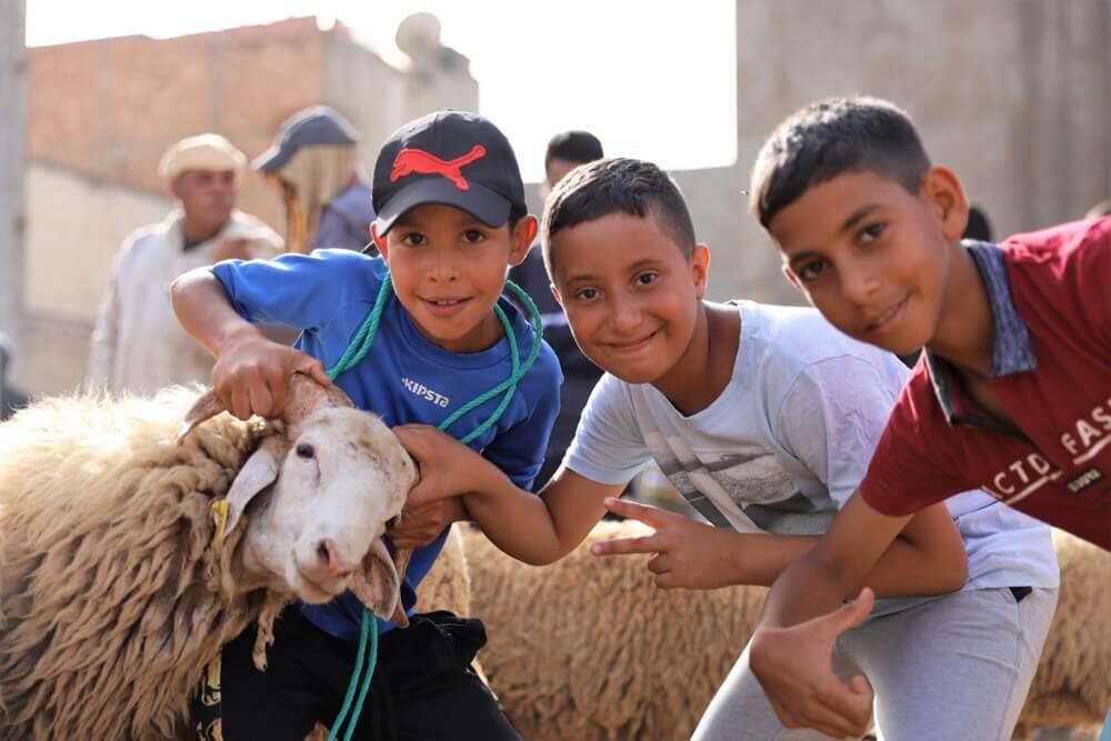 أطفال يحتفلون بعيد الأضحى بملابس العيد التقليدية، يبتسمون ويتبادلون الفرح في أجواء احتفالية مليئة بالبهجة.