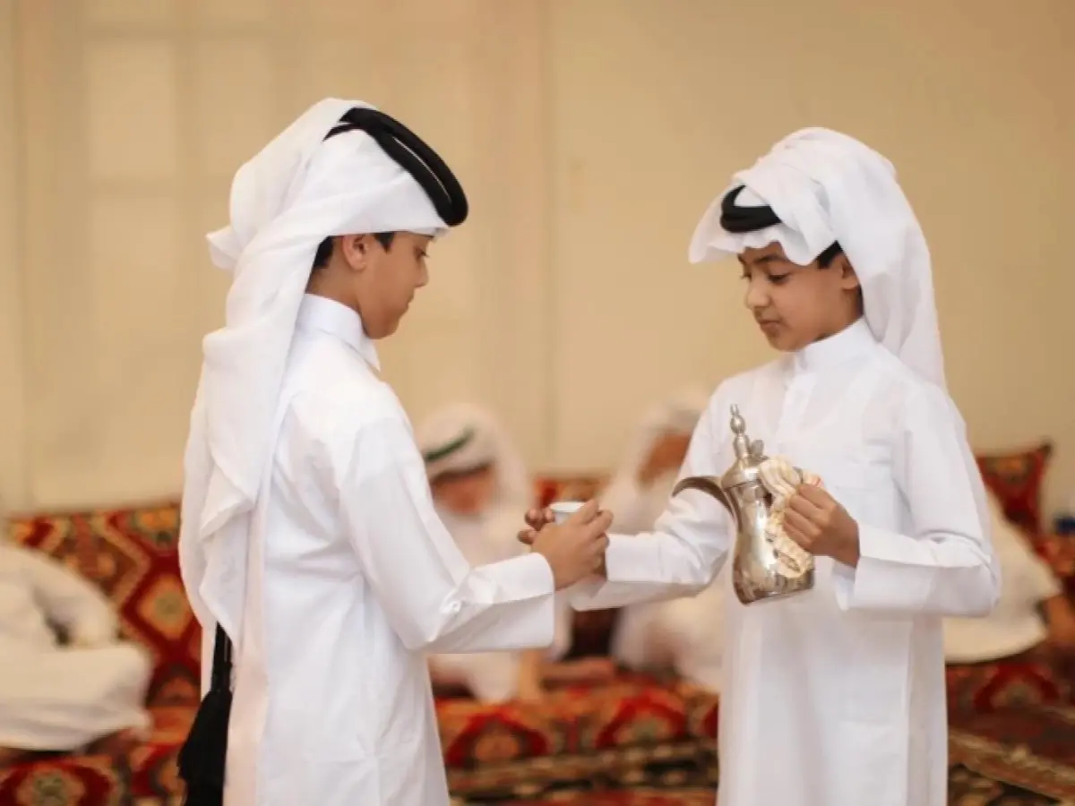 أطفال يقدمون القهوة العربية التقليدية للضيوف خلال احتفالات العيد، مرتدين ملابس تراثية وفي أجواء عربية أصيلة.