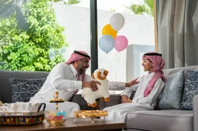 أب يقدم هدية لابنه في أجواء عائلية دافئة خلال العيد، وسط مشاعر الفرح والمحبة