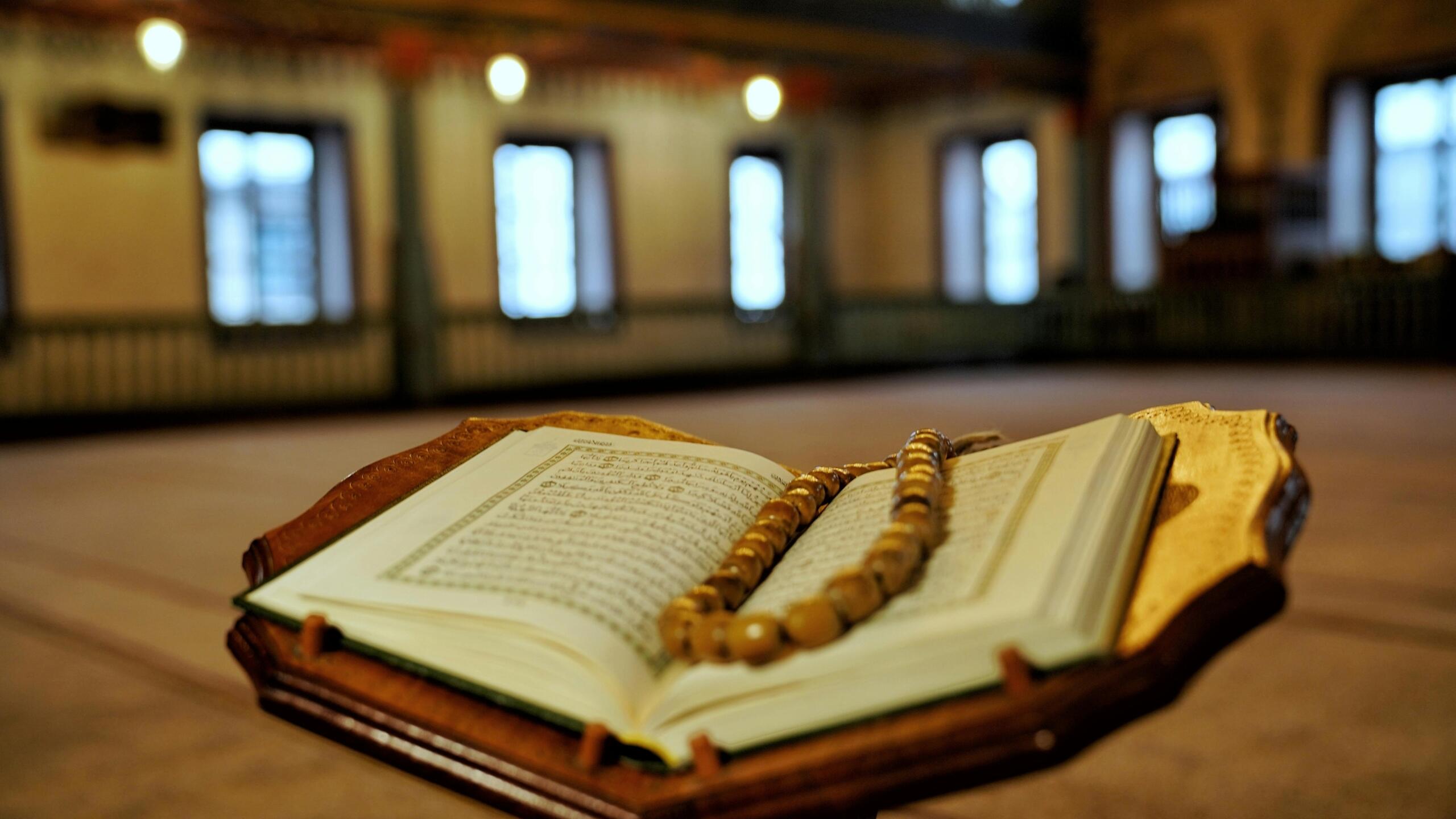 نسخة من القرآن الكريم موضوعة داخل مسجد بإضاءة هادئة وأجواء روحانية تعكس السكينة والعبادة.