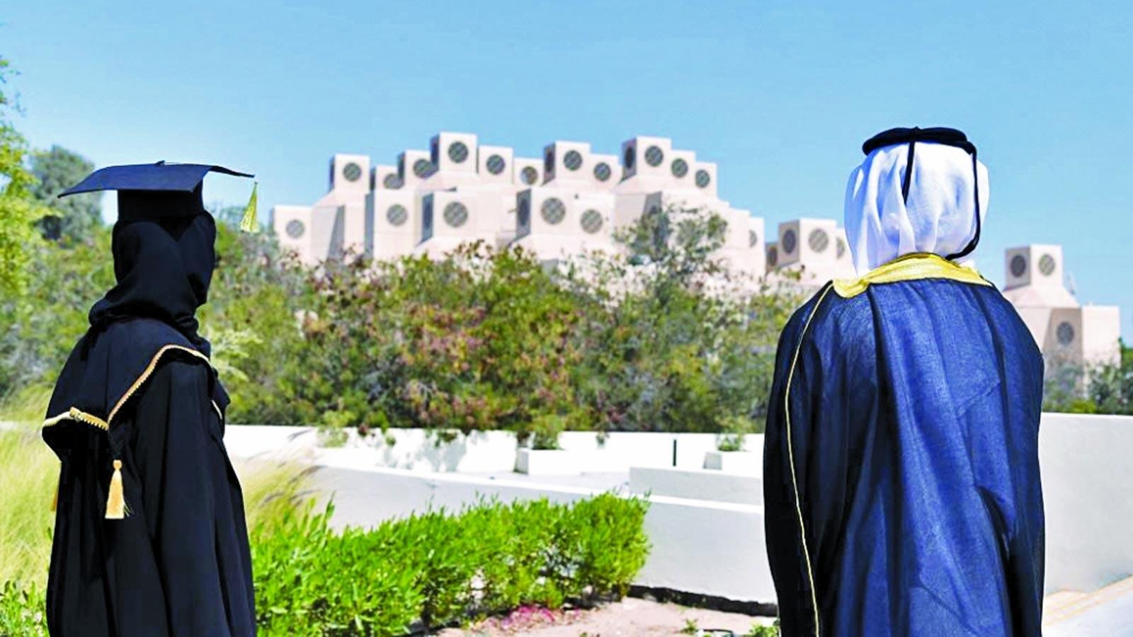 صورة لخريج وخريجة ينظران من الخلف نحو مبنى جامعة قطر المميز وسط أجواء مشمسة.