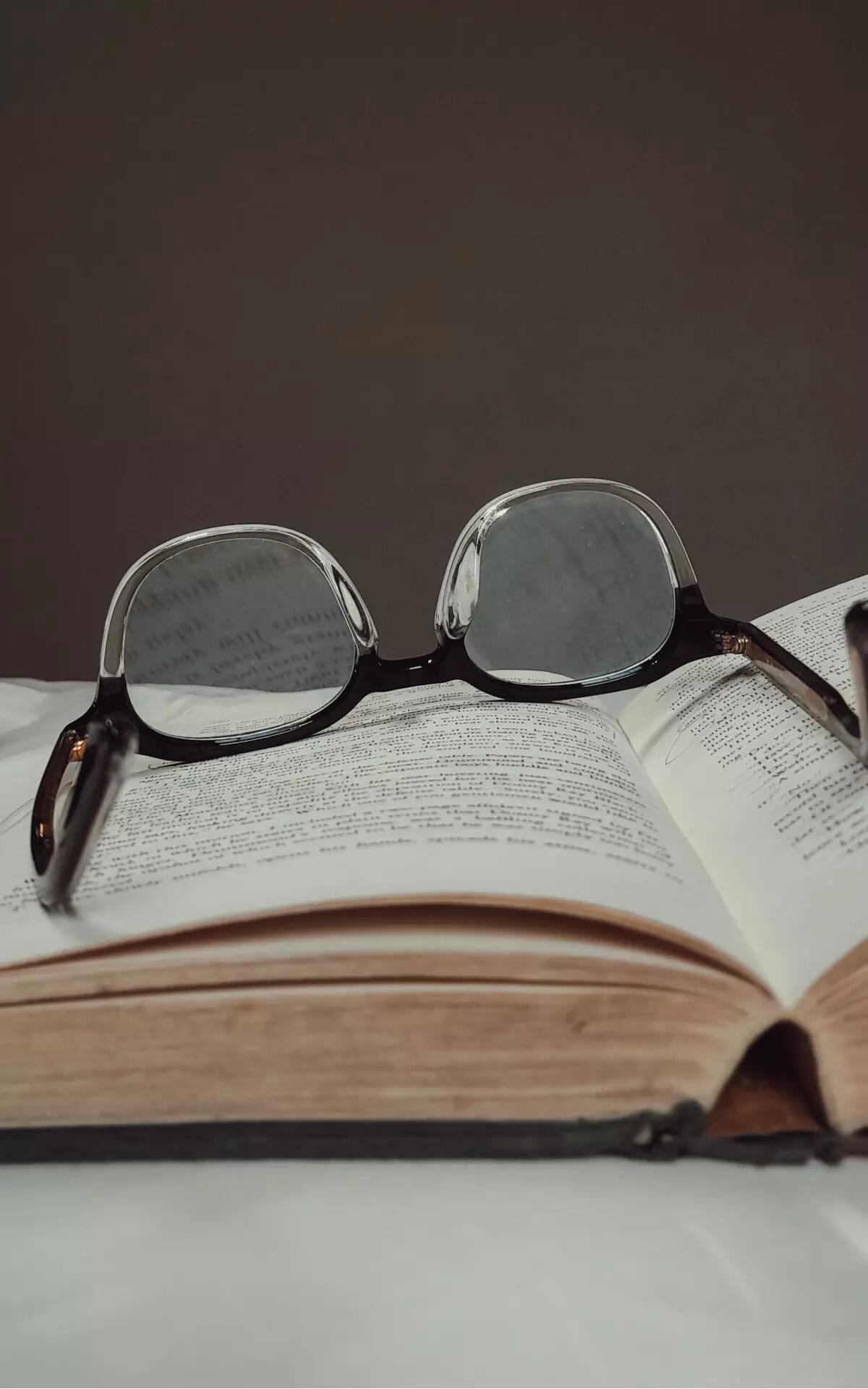 كتاب باللغة الإنجليزية ونظارات موضوعة فوقه.