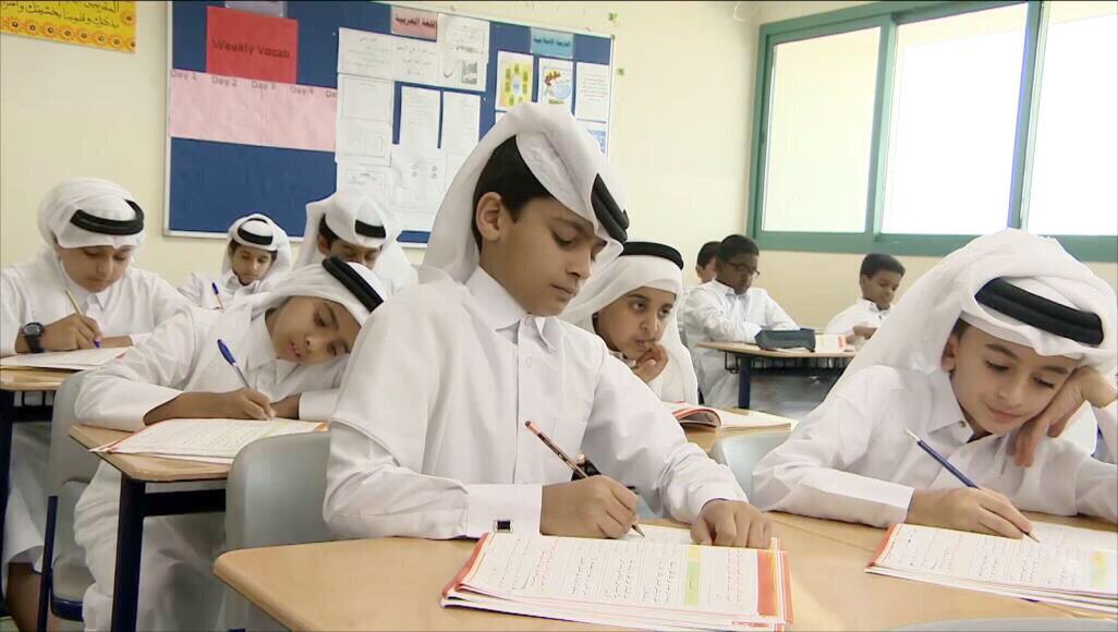 طلبة يجلسون على مقاعد الدراسة في إحدى المدارس القطرية، ويقومون بحل الواجبات الصفية. تبدو البيئة الصفية مجهزة بأفضل التجهيزات مما يدلل على مستوى التعليم الجيد في قطر.