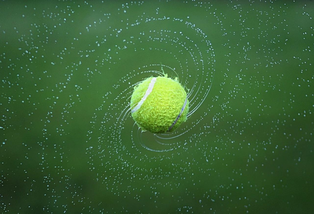 Ein Tennisball in Nahaufnahme dreht sich um seine Achse. Welche Kräfte hier auf ihn wirken, wird im Fachgebiet der Bewegung untersucht.