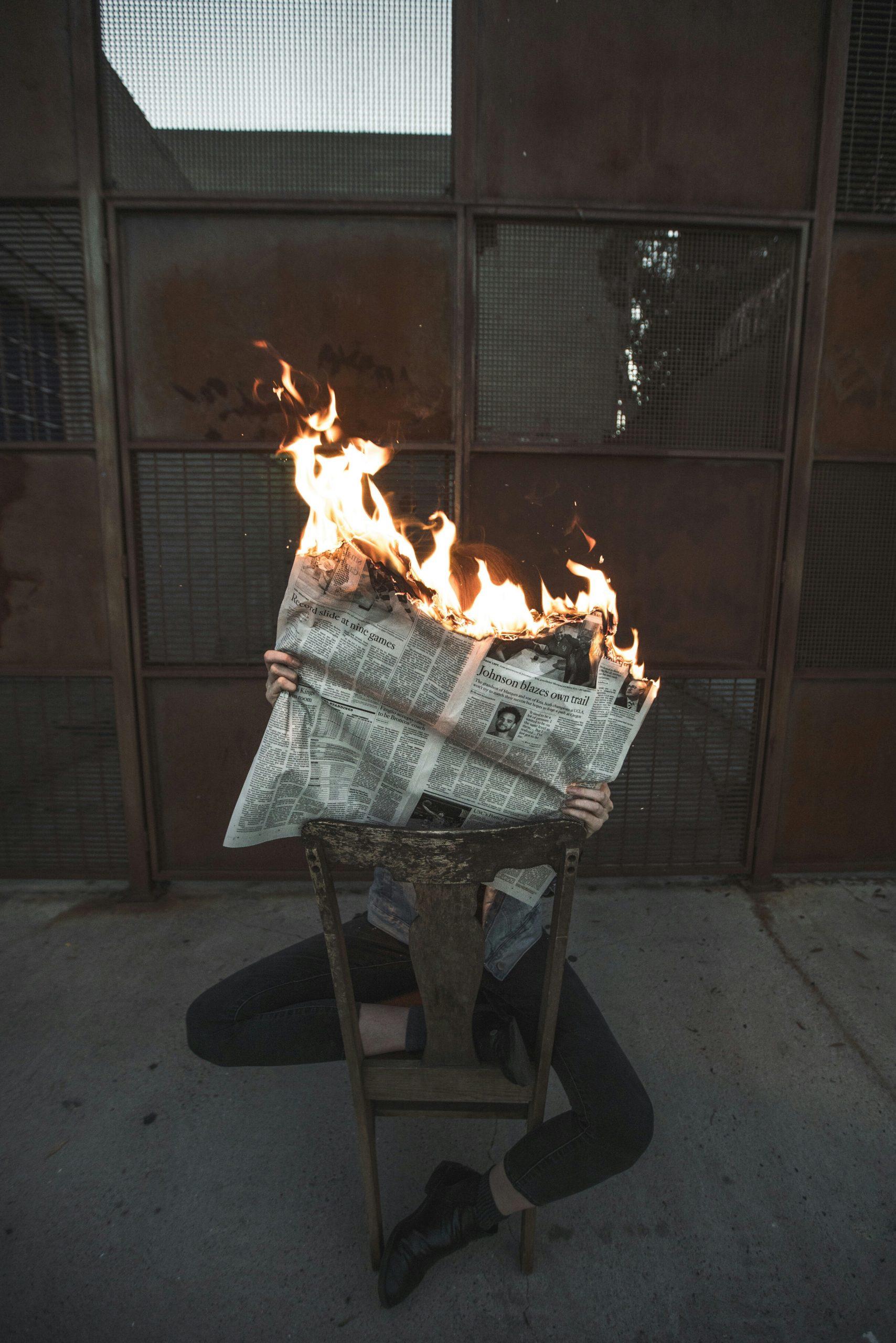 Un homme tient un journal en feu.