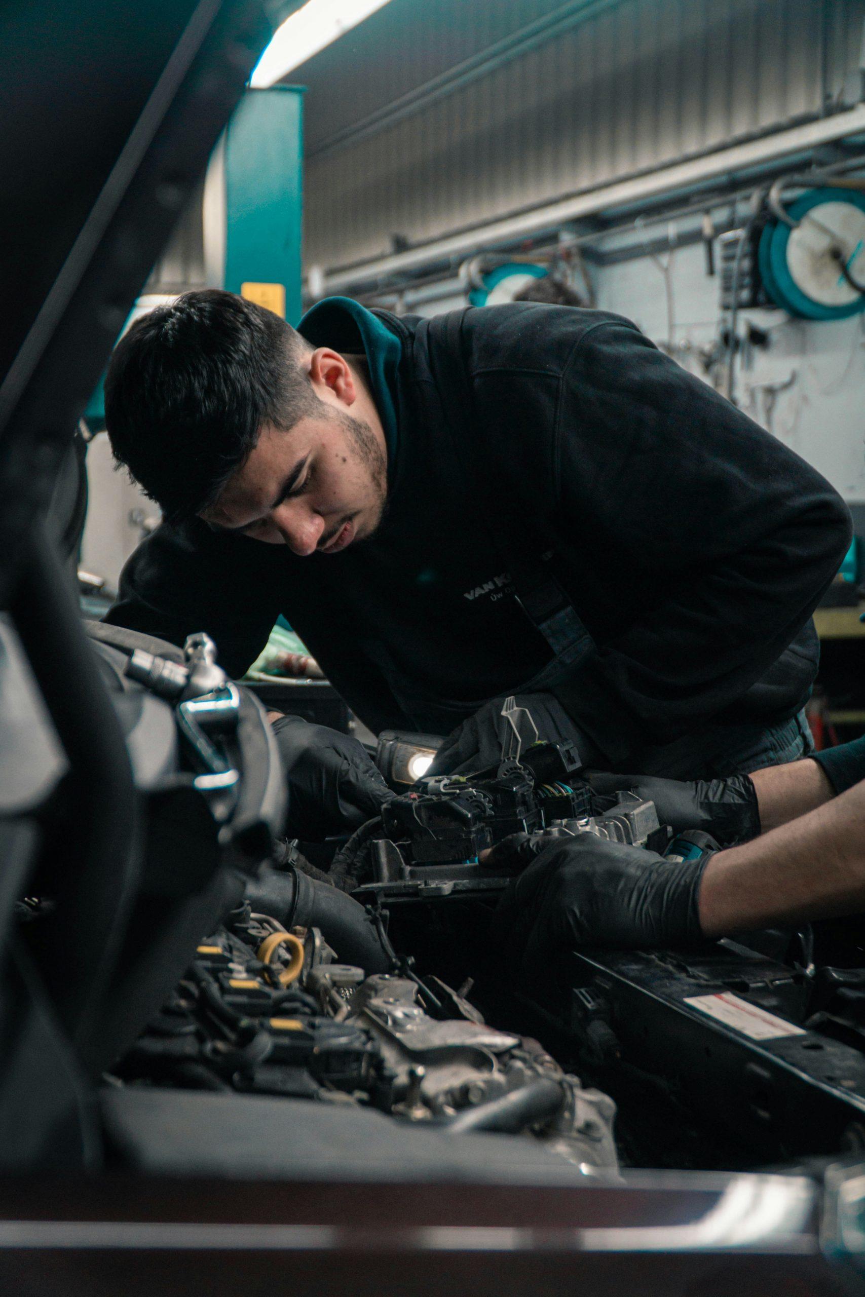 Un homme répare un moteur de voiture.