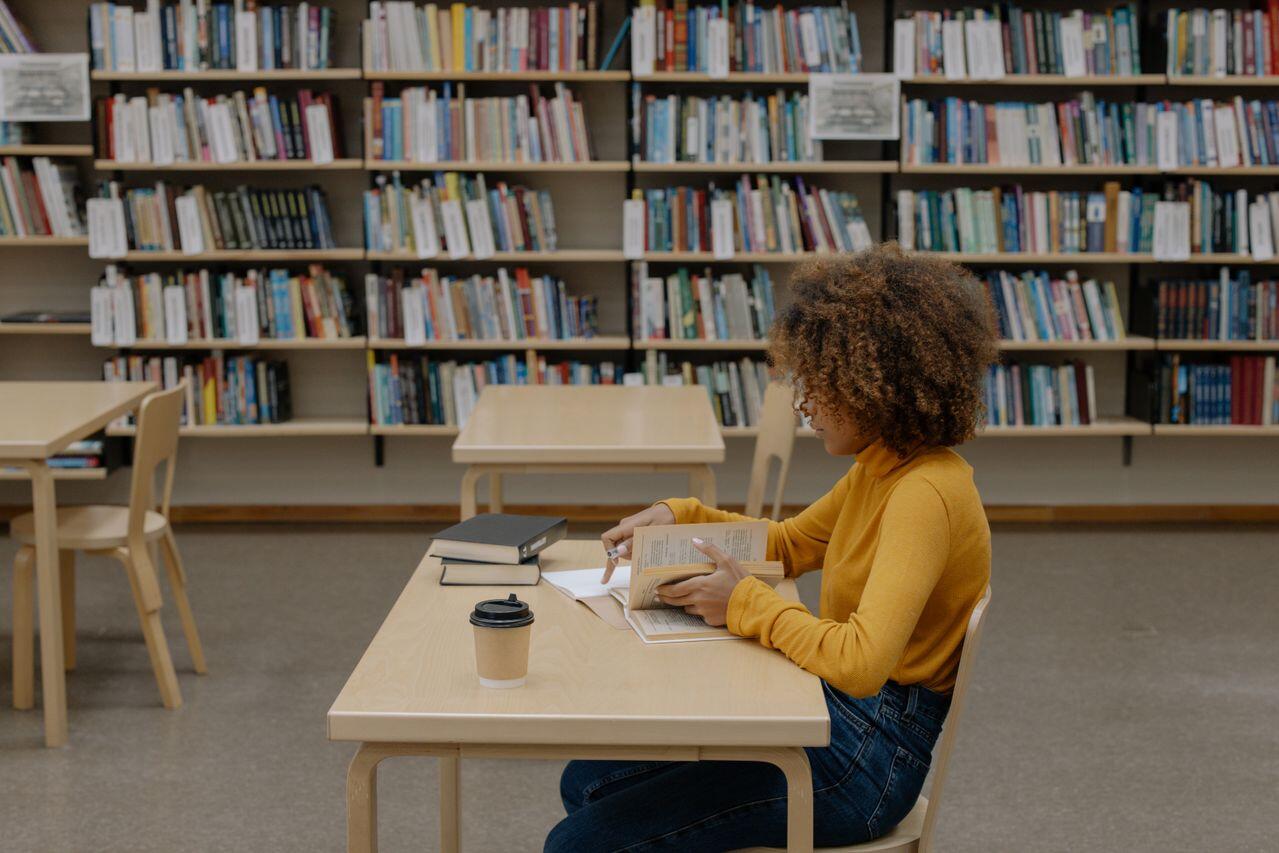 jeune femme en pull moutarde etudiant a la bibliotheque