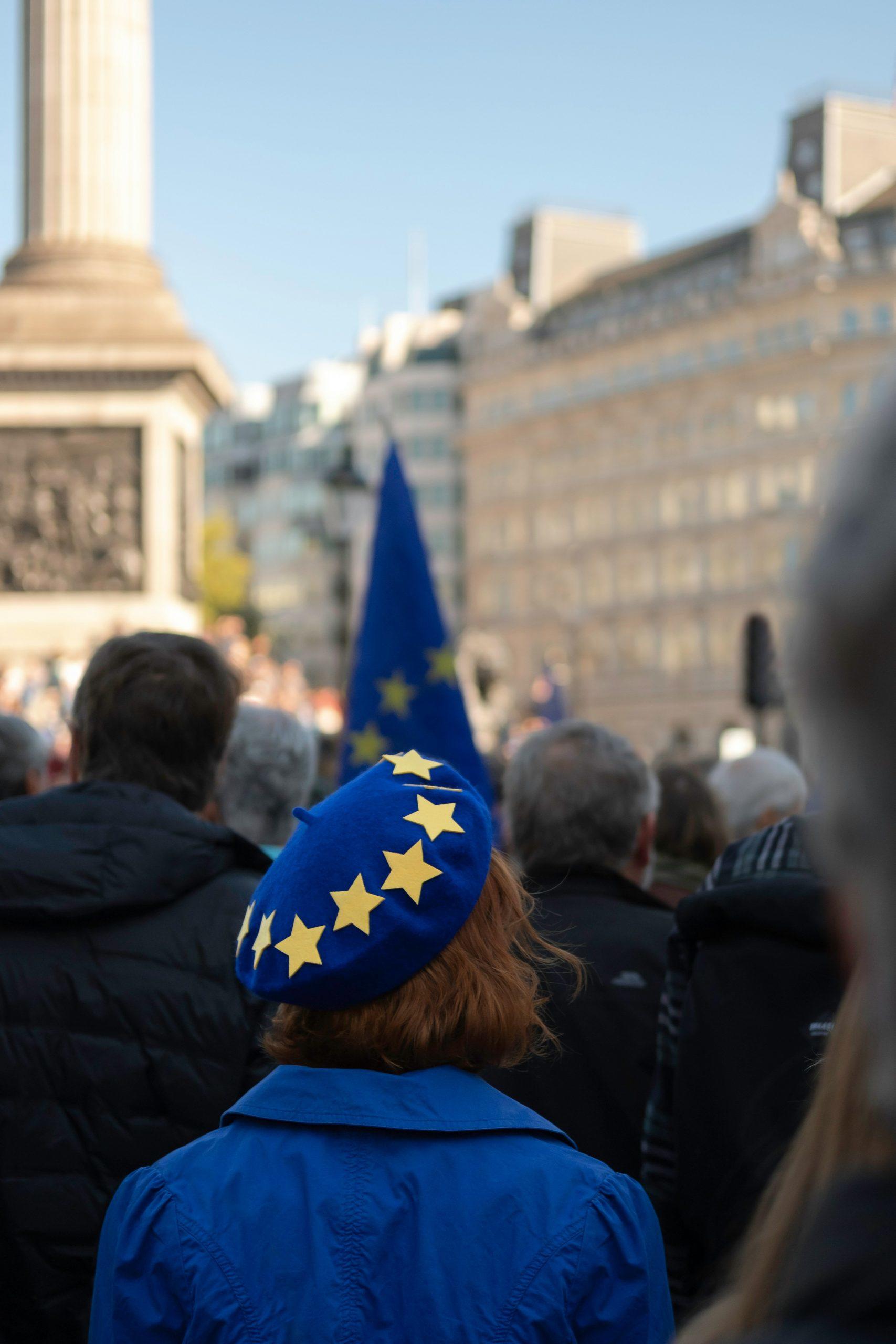 Une femme de dos porte un béret signé du drapeau européenne.