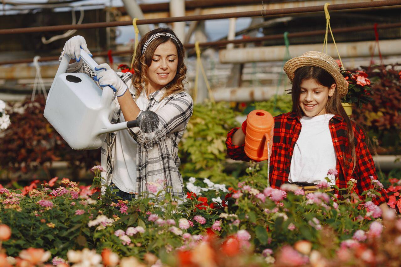 une mère et sa fille arrosant leur jardin