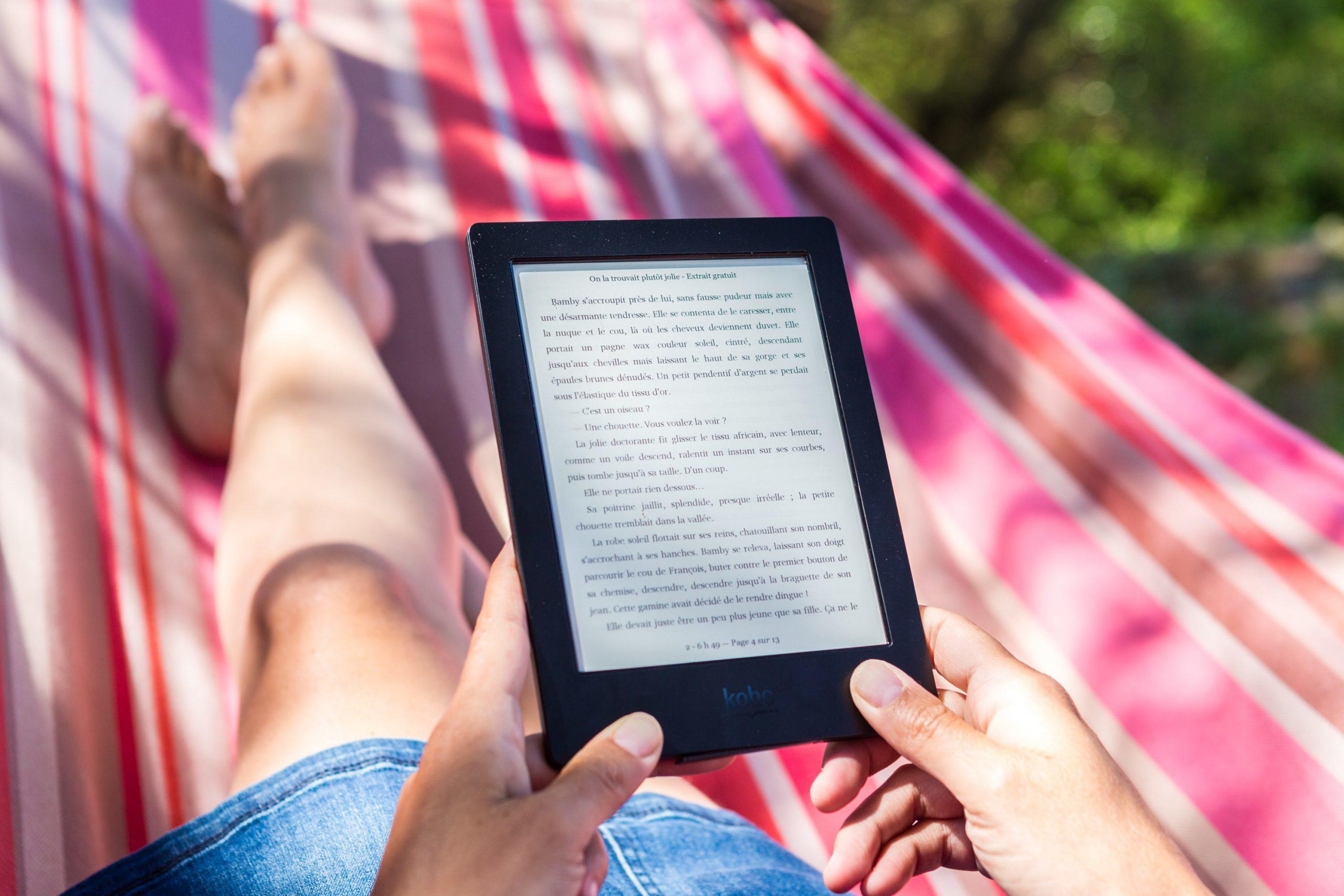 Une femme lit un livre sur une tablette numérique.