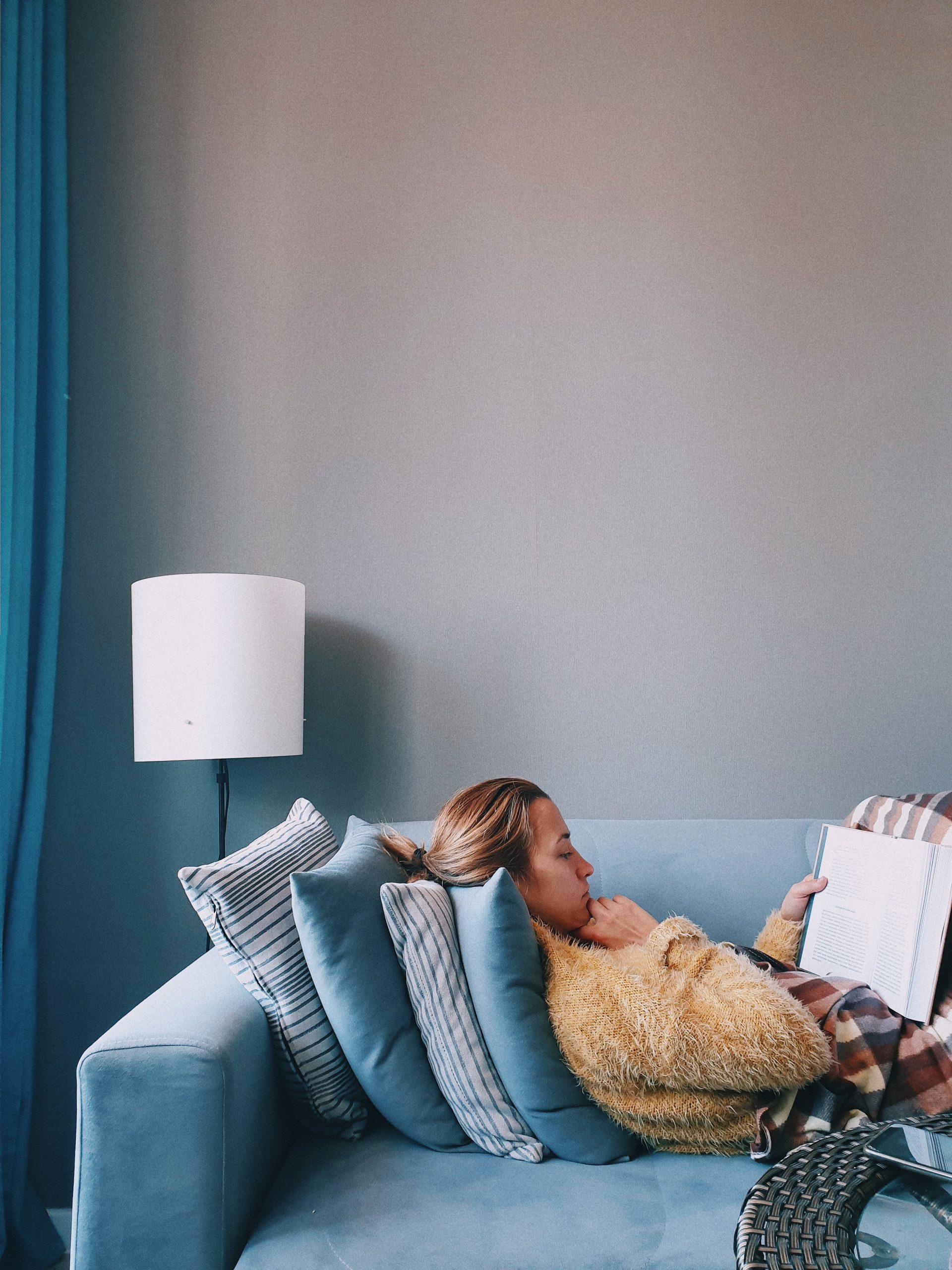 Une femme lit sur son canapé.